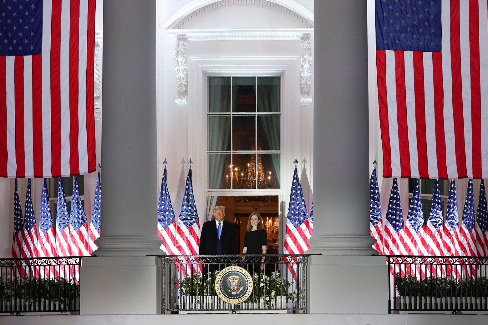 Trump and Barrett stand on a balcony overlooking the South Lawn, with American flags all around them