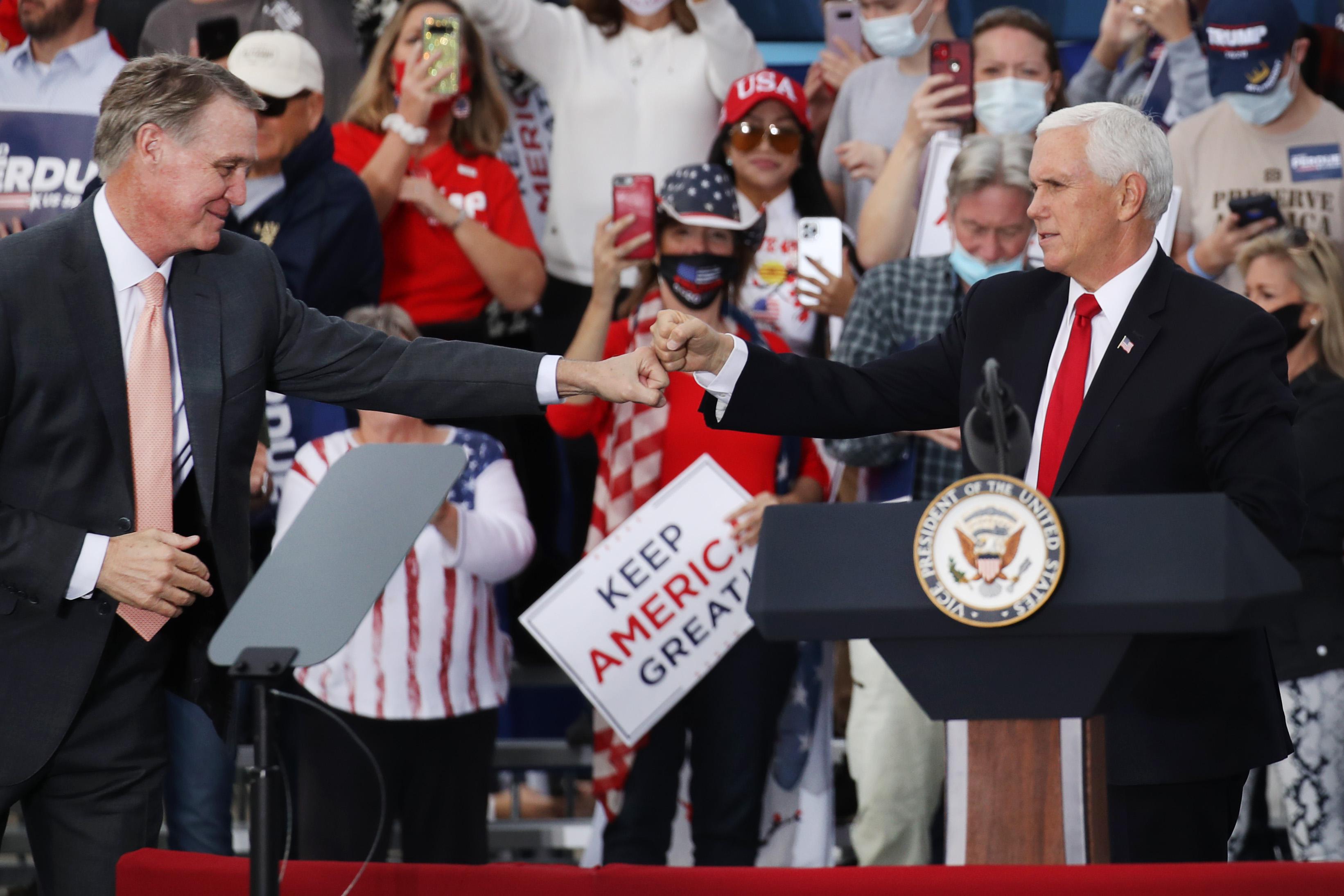 Pence and Perdue fist-bumping on stage