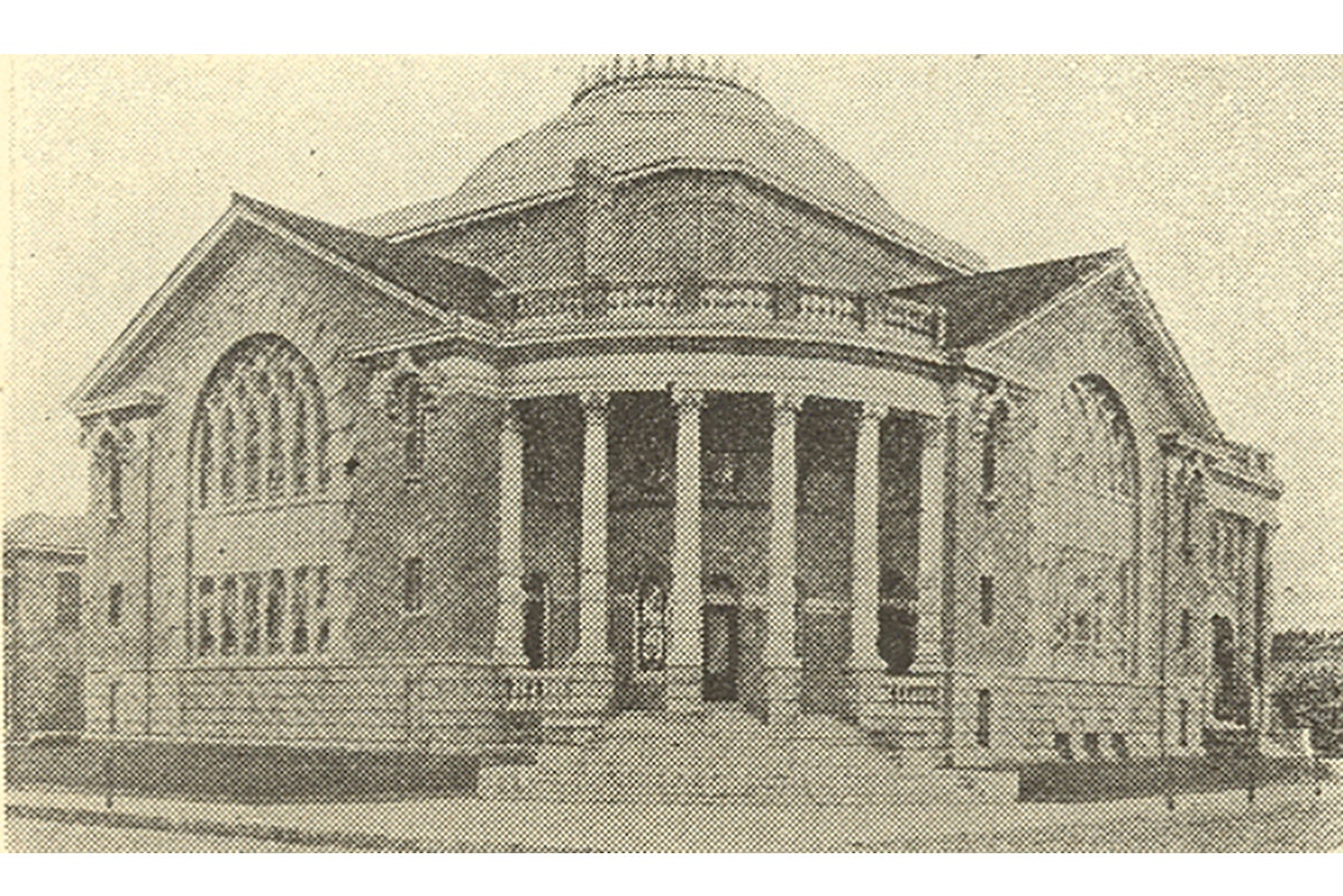A large stone church building, with stained glass windows, columns, and a massive central dome.