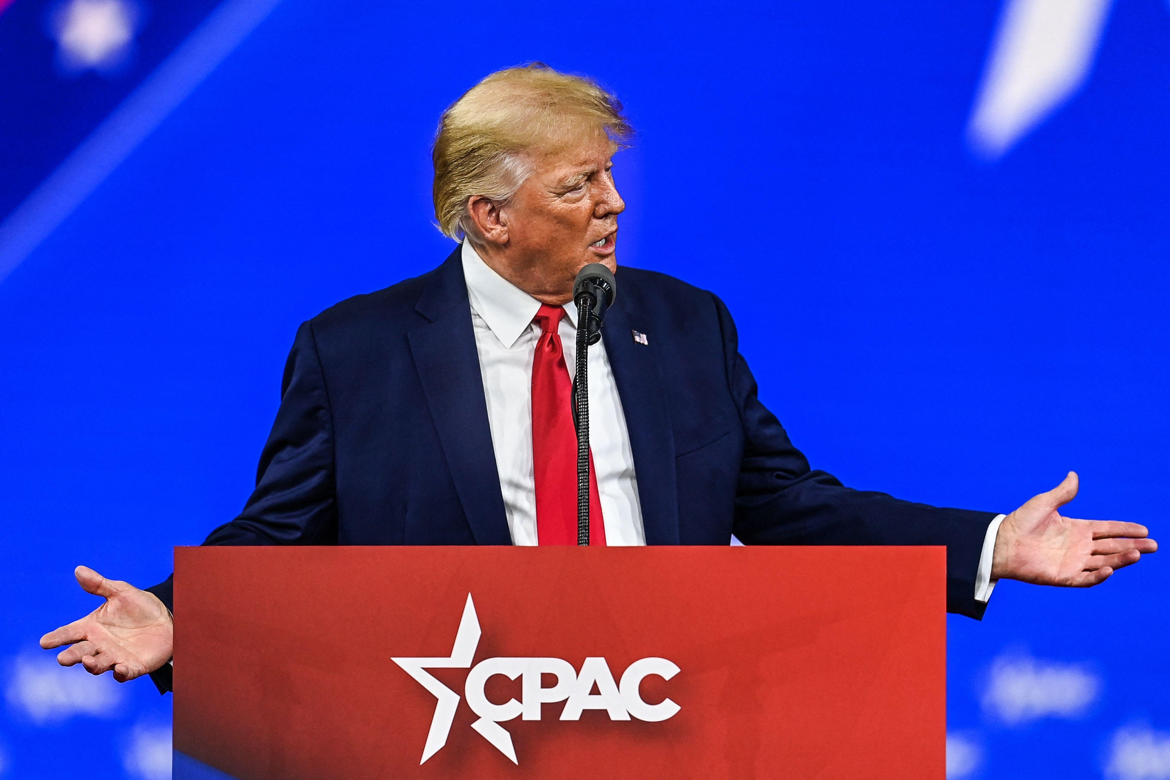 Trump gesticulates and speaks into a CPAC-branded lectern.