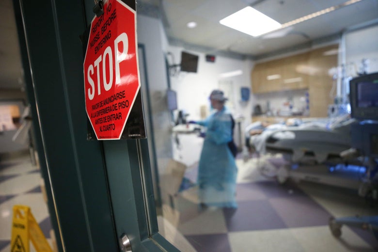 A red stop sign is seen on a window looking into a hospital room.
