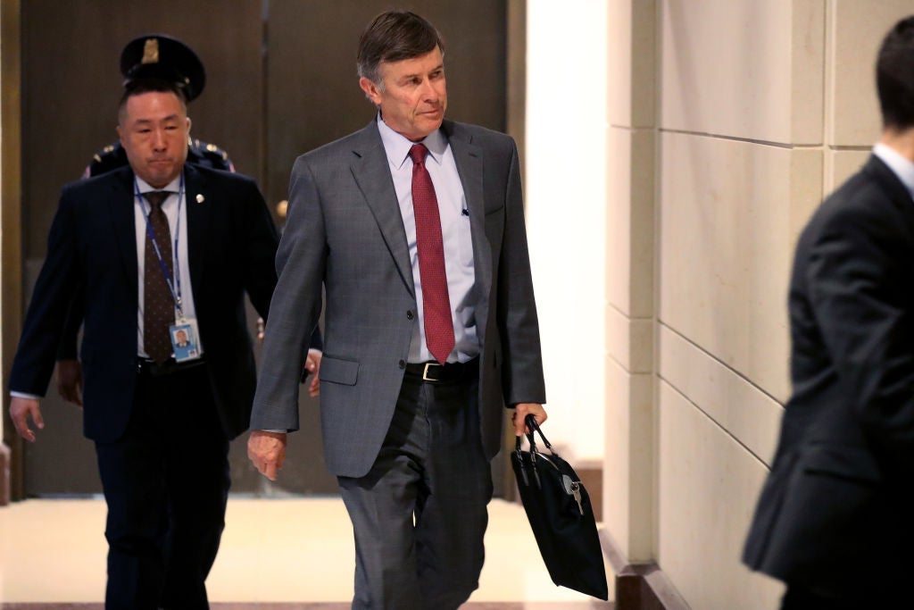 Joseph Maguire strides through a hallway while carrying a briefcase.