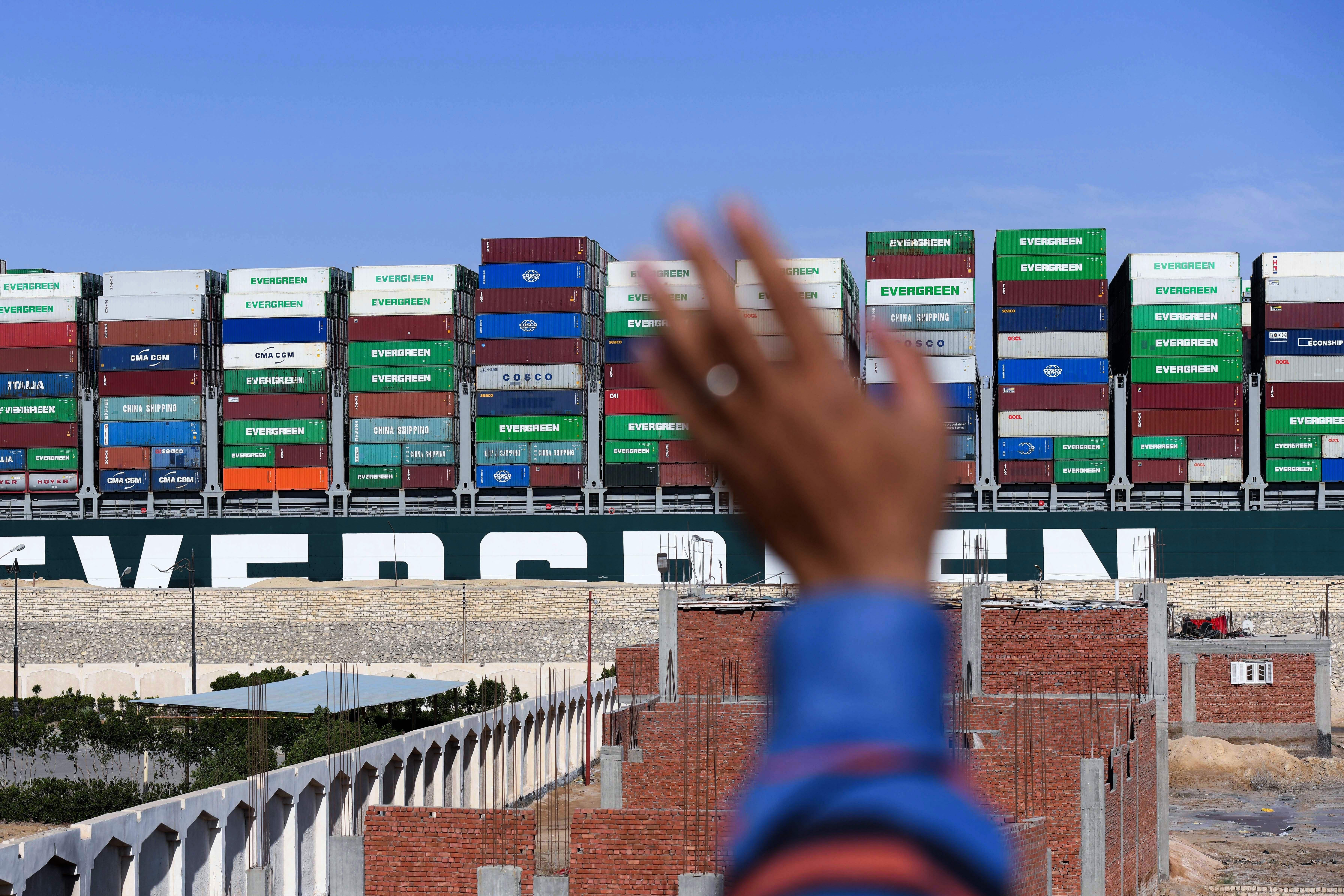 A man waves at the Panama-flagged MV "Ever Given" container ship as it is tugged in Egypt's Suez Canal after it was fully dislodged from the banks, near Suez city, on March 29, 2021. 