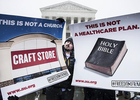 Activists hold signs outside the Supreme Court on March 25, 2014, as the court hears arguments in Sebelius v. Hobby Lobby.