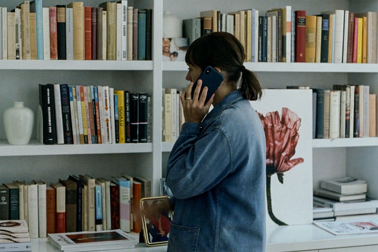 Rashida Jones on the phone, standing in front of her bookshelves.