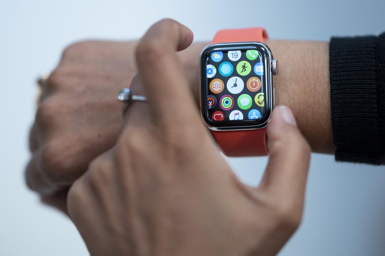 A left hand reaches for an Apple Watch on a right hand.