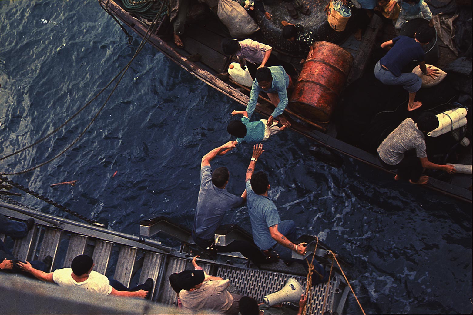 South China Sea Crewmen of the amphibious cargo ship USS Durham (LKA-114) take Vietnamese refugees aboard a small craft in this undated photo.