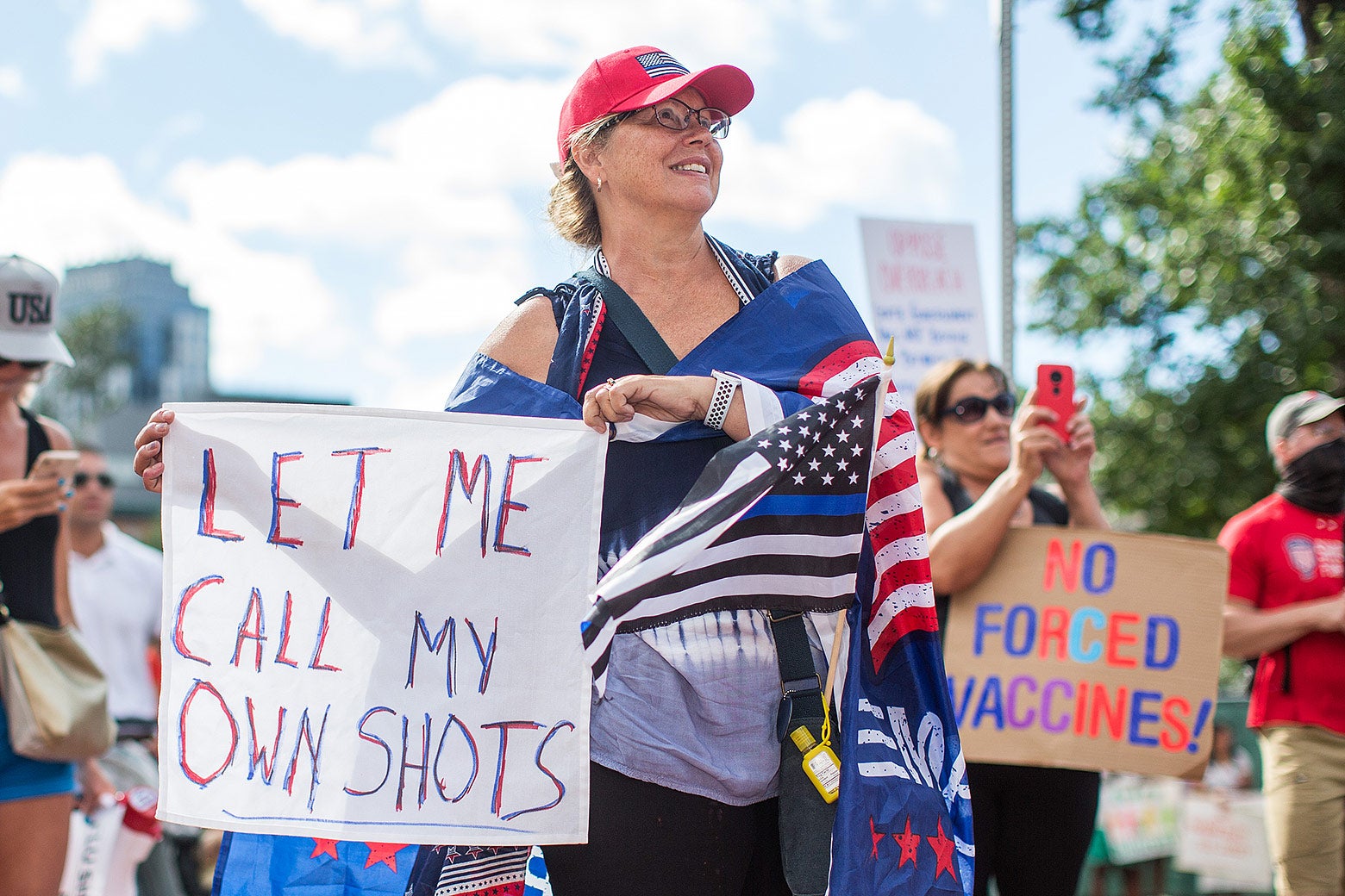 A woman holds up a sign that says, "LET ME CALL MY OWN SHOTS."