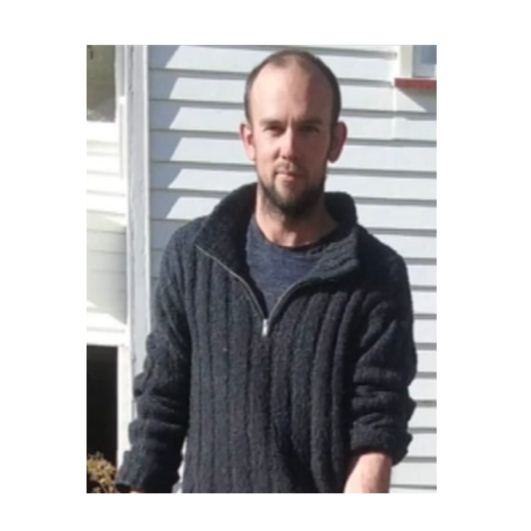 A balding white man in his 30s wearing a gray sweater.