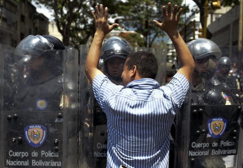 A supporter of Leopoldo Lopez, an ardent opponent of Venezuela's socialist government facing an arrest warrant after President Nicolas Maduro ordered his arrest on charges of homicide and inciting violence, faces riot police during a march, on February 18, 2014, in Caracas. 