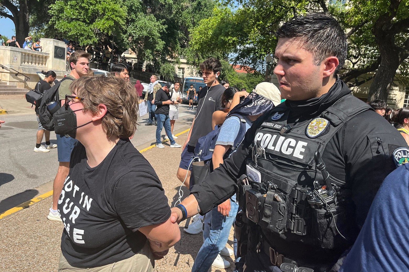 A police officer leads away an arrested protestor. 