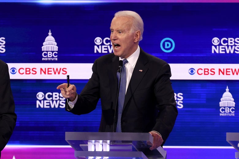 Joe Biden, in a dark suit and blue tie, stands at a lectern in front of a CBS News backdrop, speaking animatedly with his mouth wide open and pointing with his right index finger.