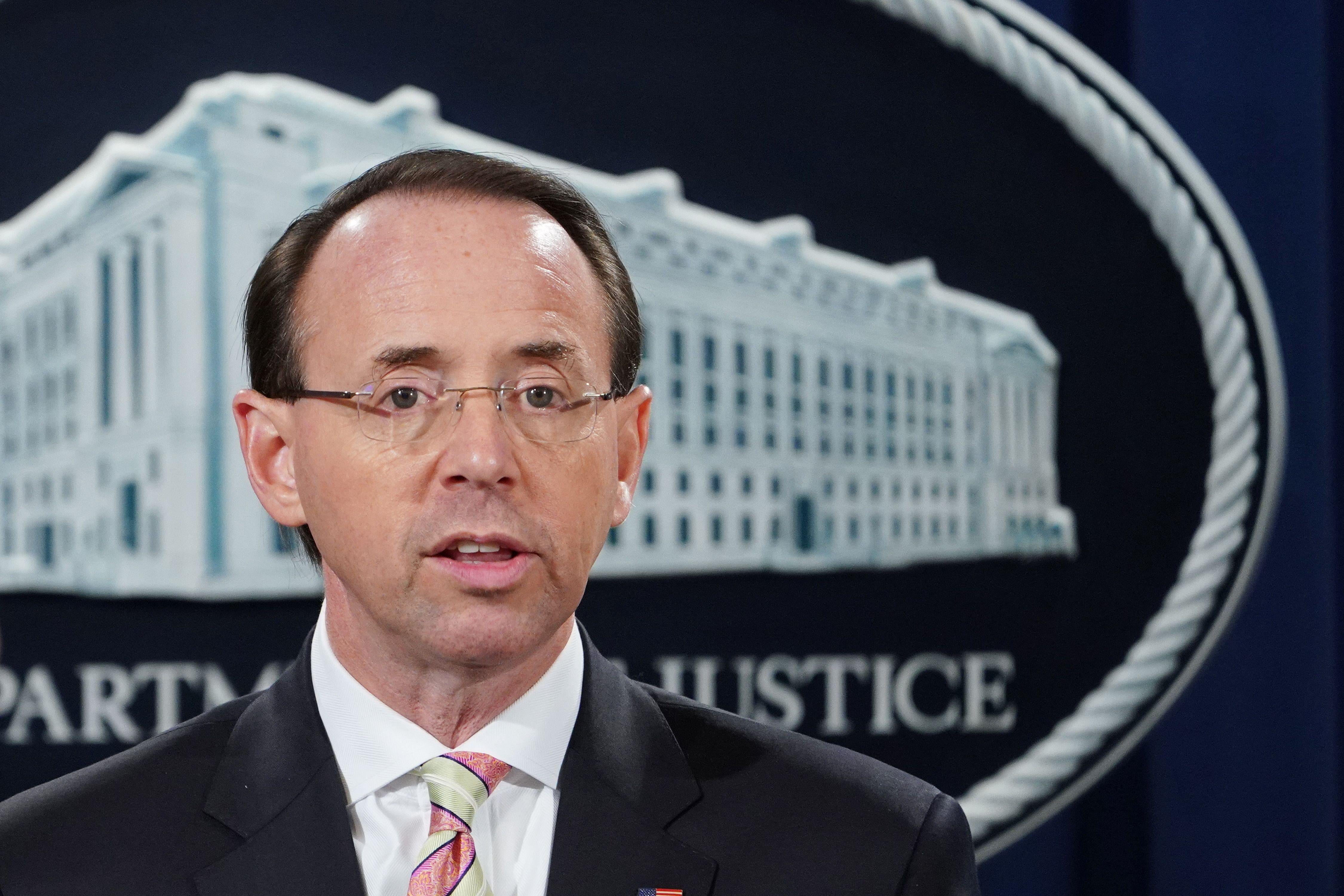 Rosenstein stands in front of a seal of the Department of Justice.