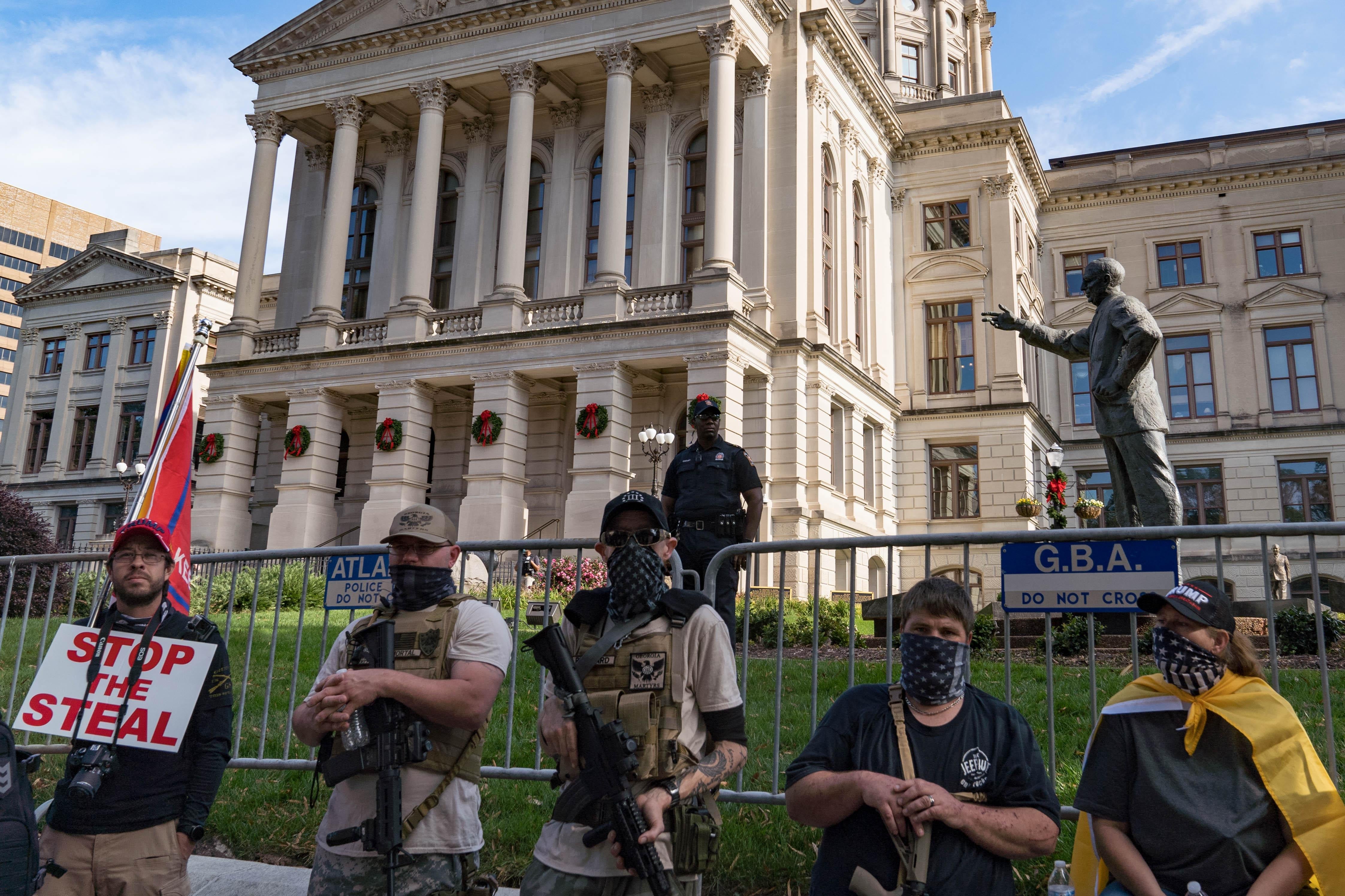 Armed men with bandannas over their faces stand in front of the Georgia State Capitol building.