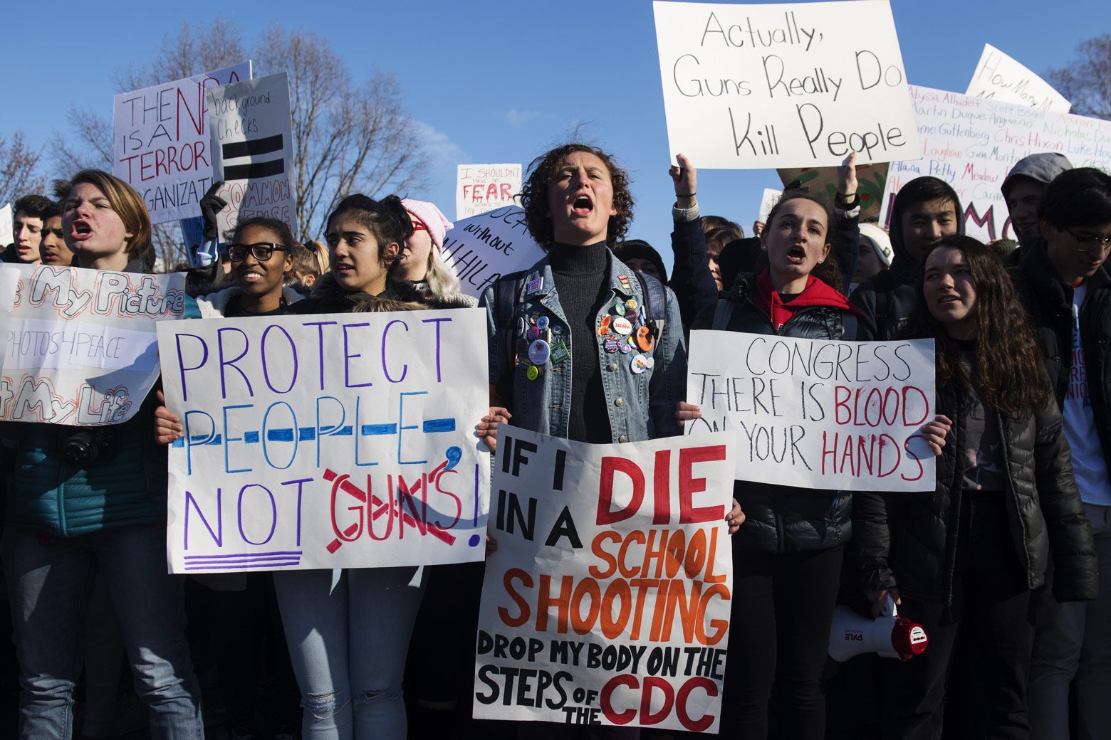 Students hold up signs saying things like, "Protect people not guns."