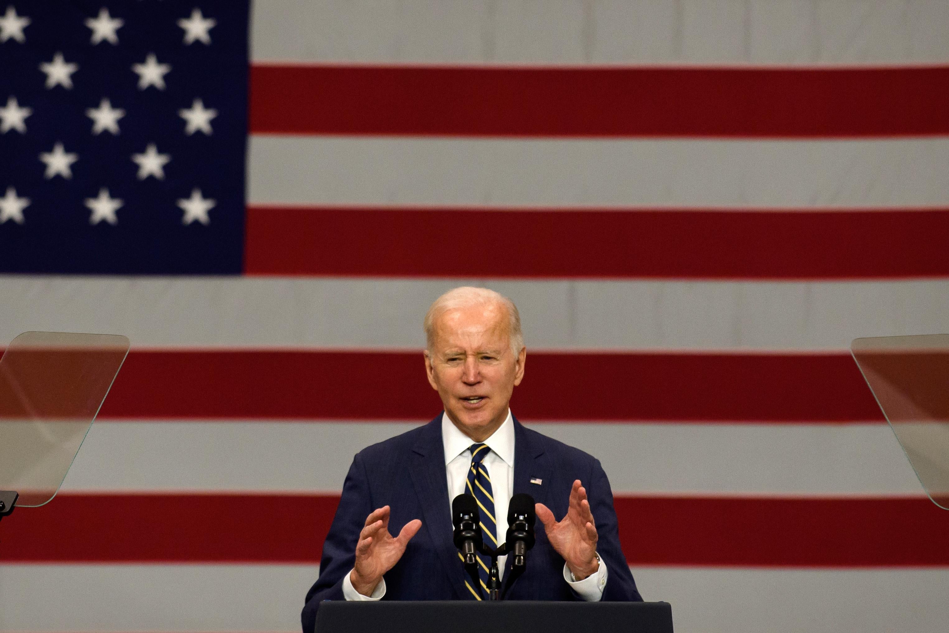Joe Biden gestures in front of an American flag.
