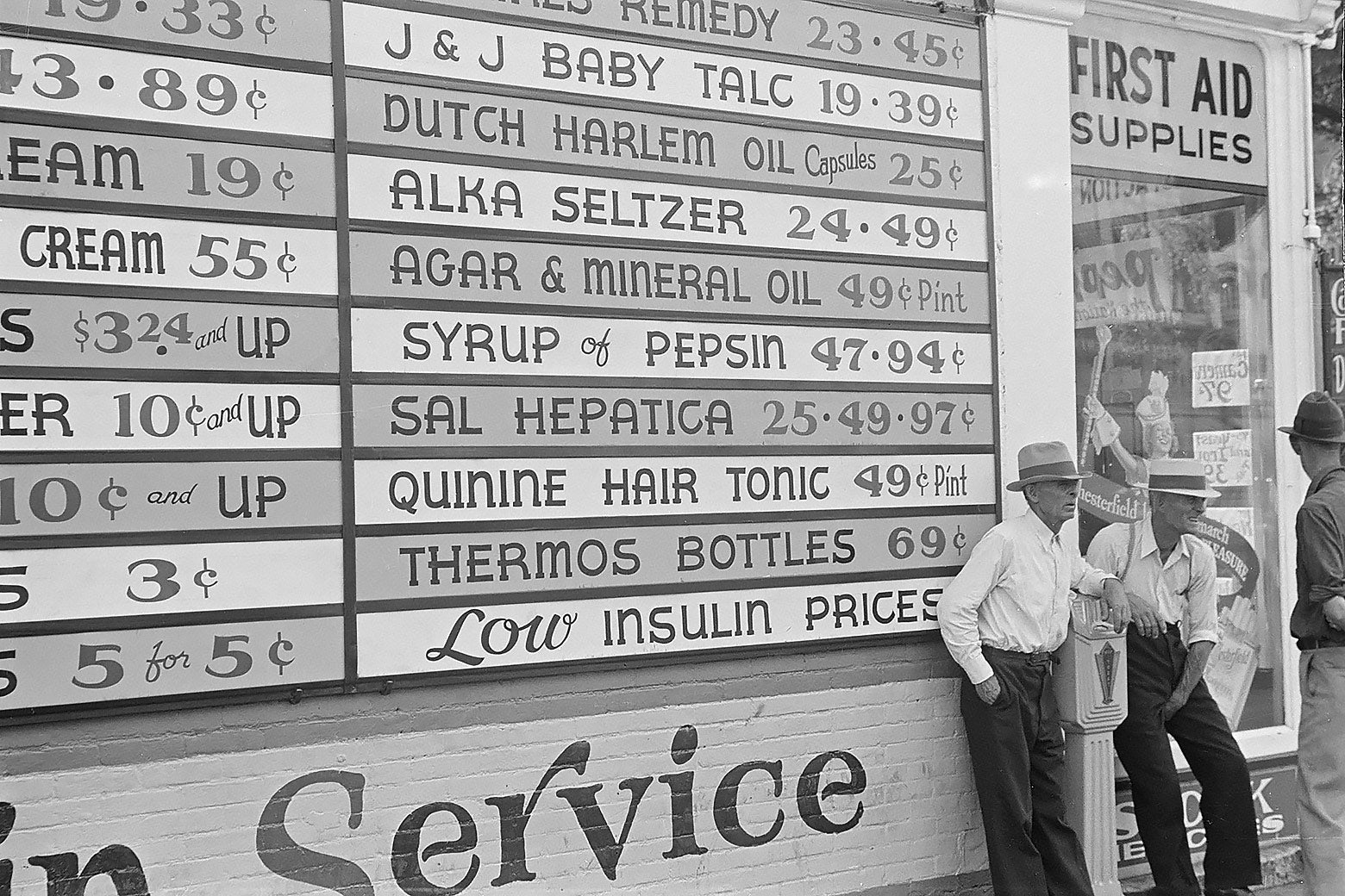 Three men standing in front of a drug story in Ohio with a large outdoor menu of drugs, tonics, and remedies, in 1938
