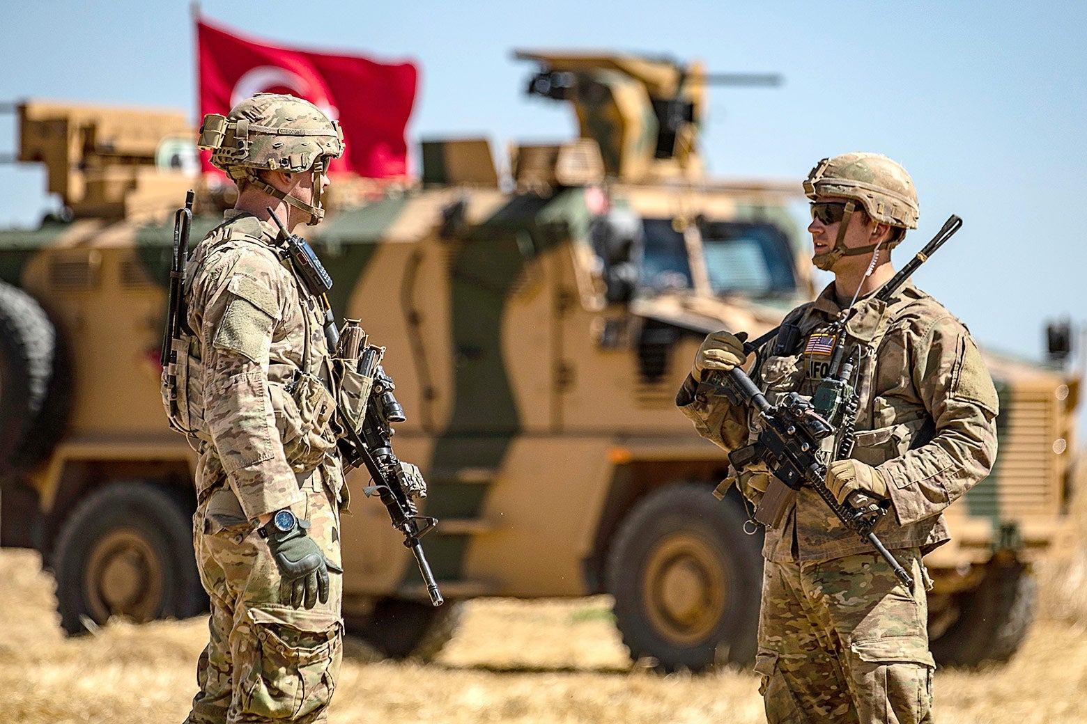 U.S. soldiers chat next to a Turkish military vehicle.