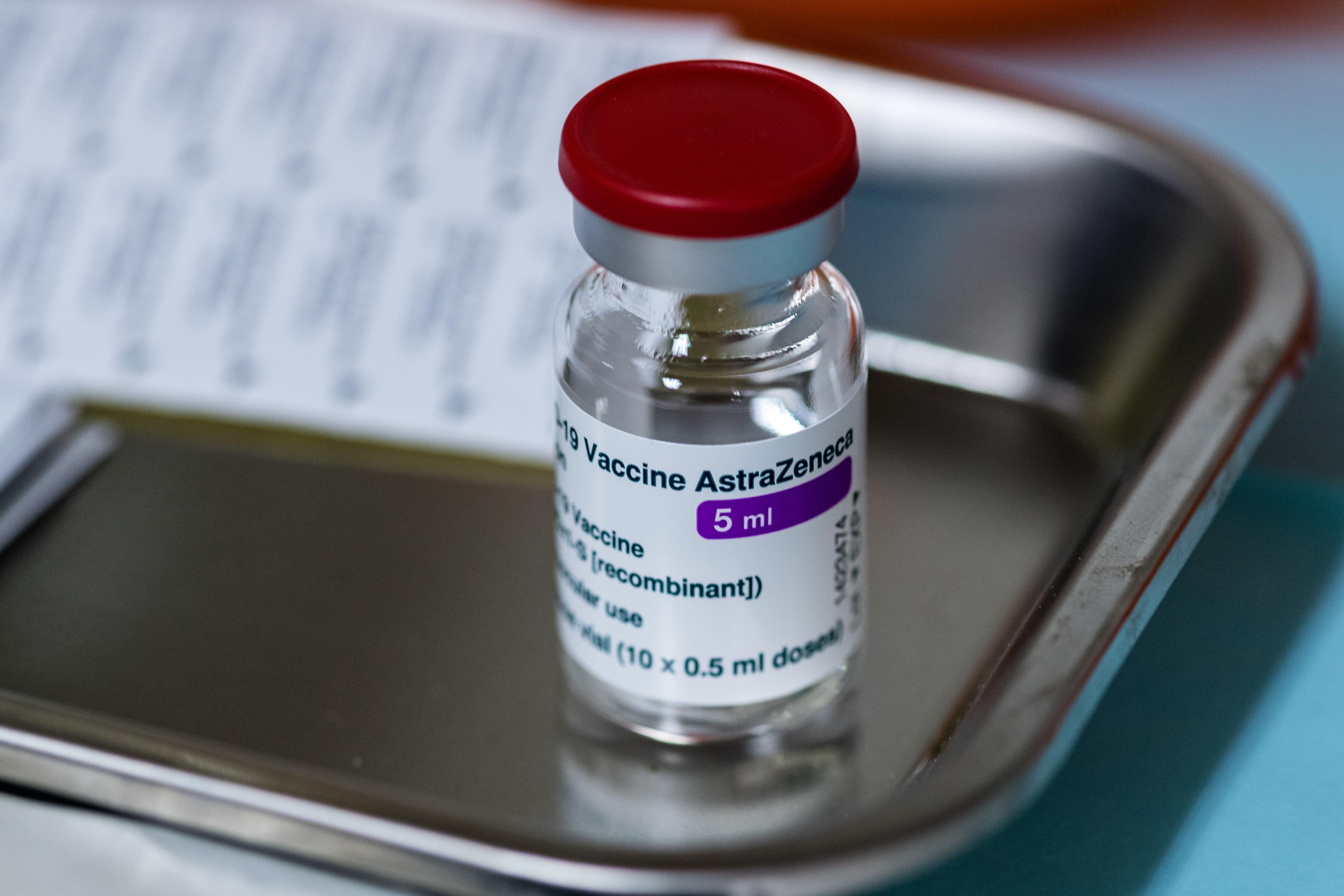 A vial of AstraZeneca COVID-19 vaccine sits on a metal tray.