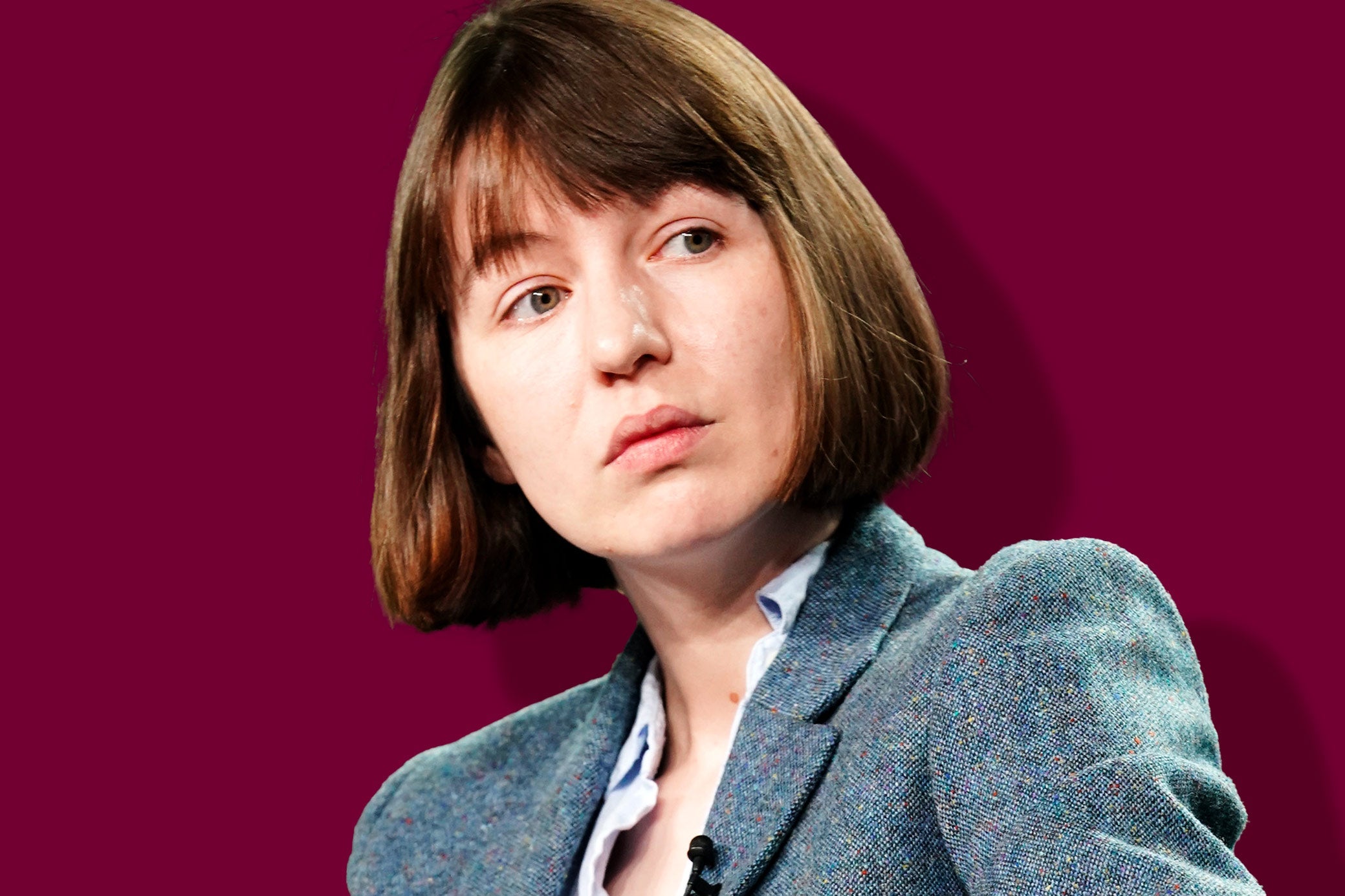 Sally Rooney in a bob haircut and a blazer, casting a sideward glance at someone off camera