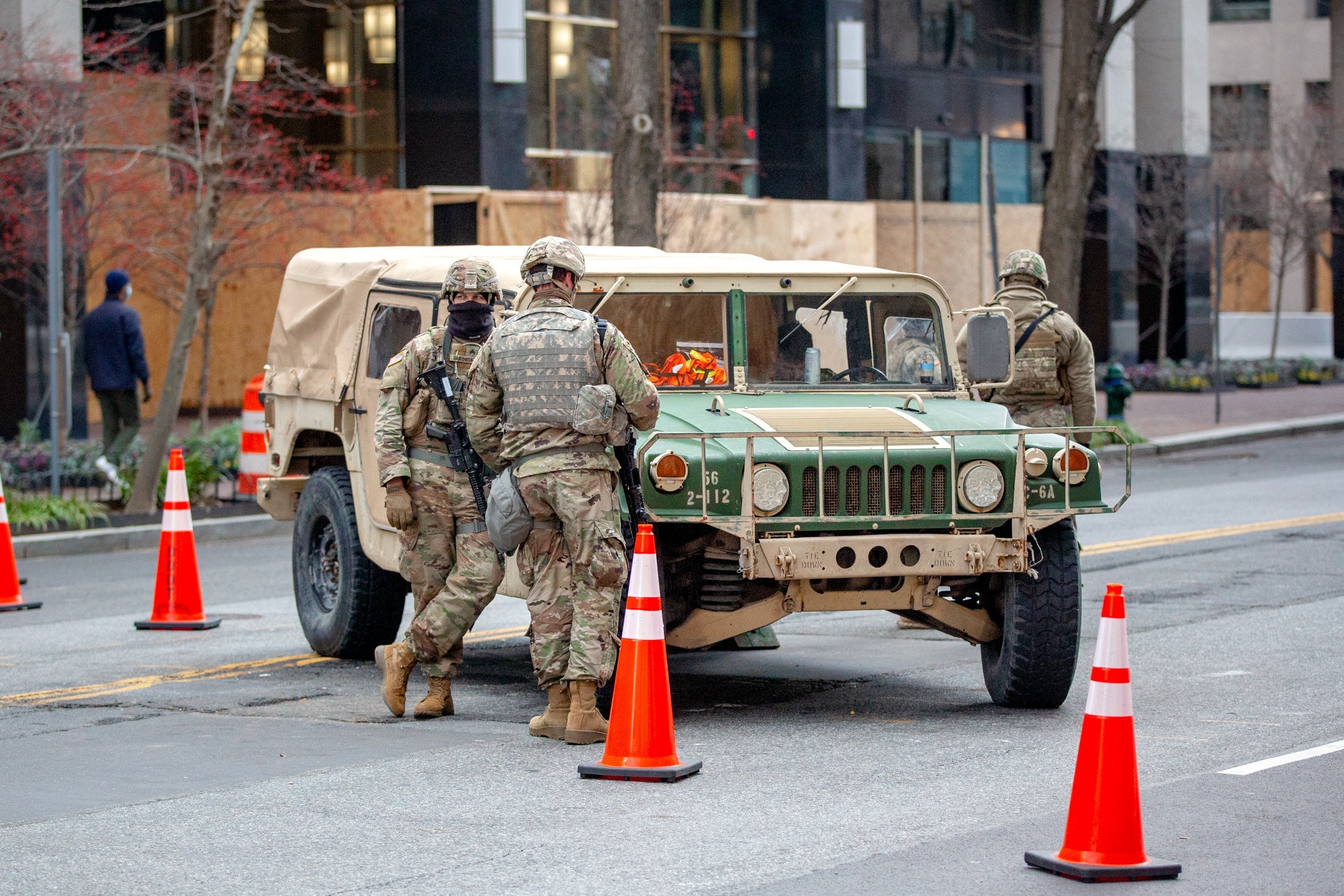 National Guard members in camo stand by a Humvee in the middle of a city street