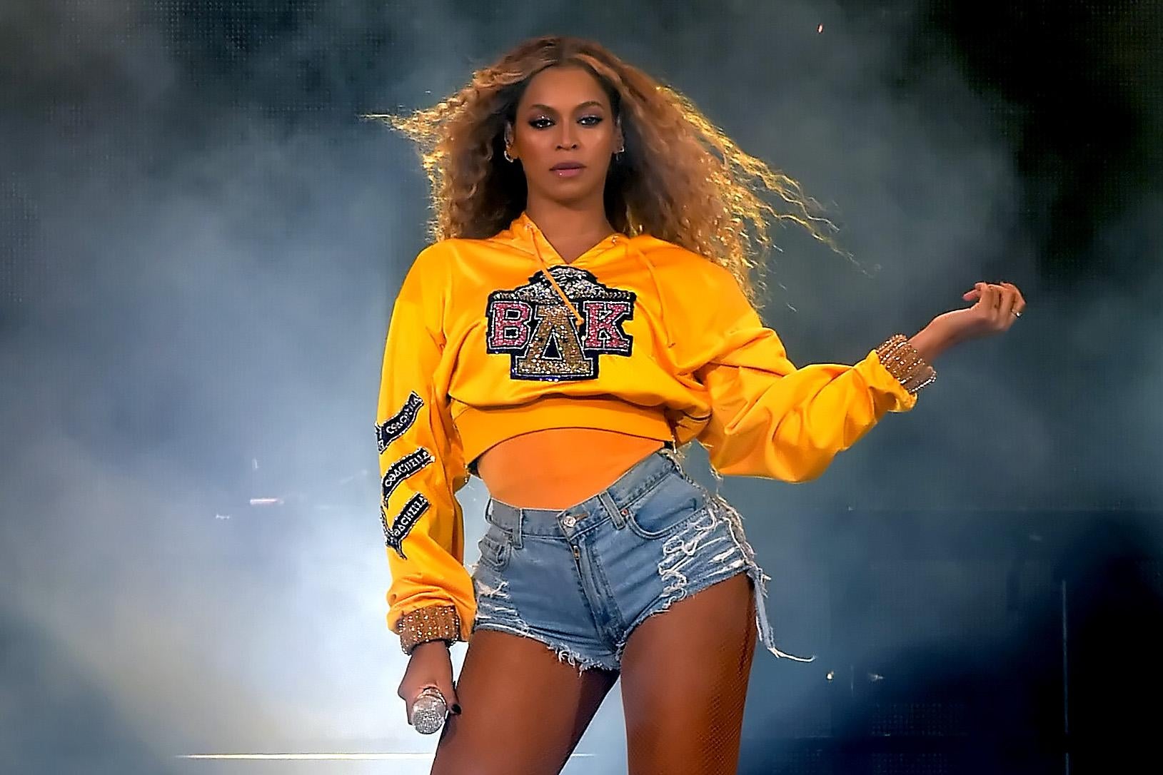 Beyonce Knowles, wearing a yellow sweatshirt and denim shorts, performs onstage during 2018 Coachella music festival.