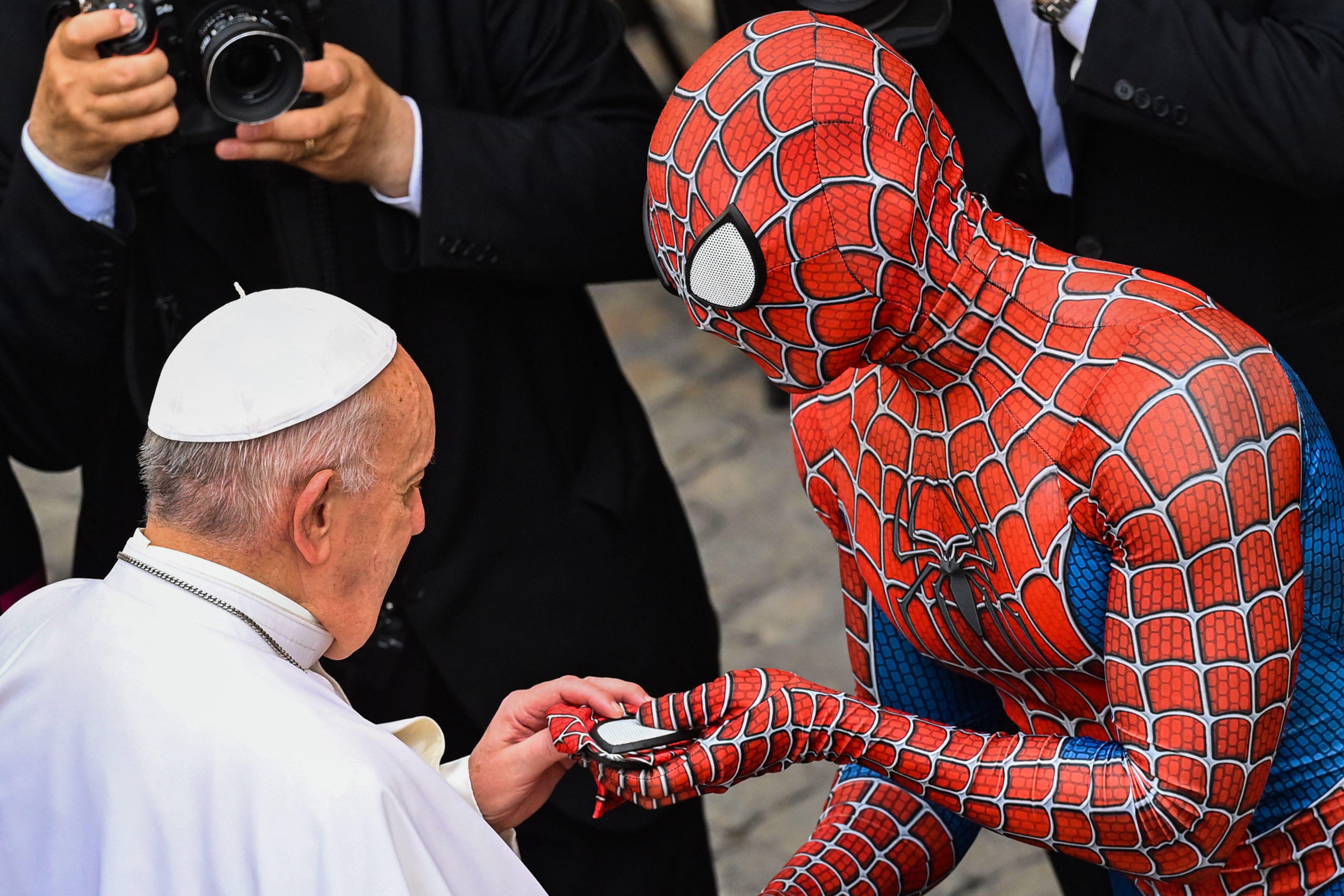 A man dressed in a Spider-Man costume hands Pope Francis a Spider-Man mask.
