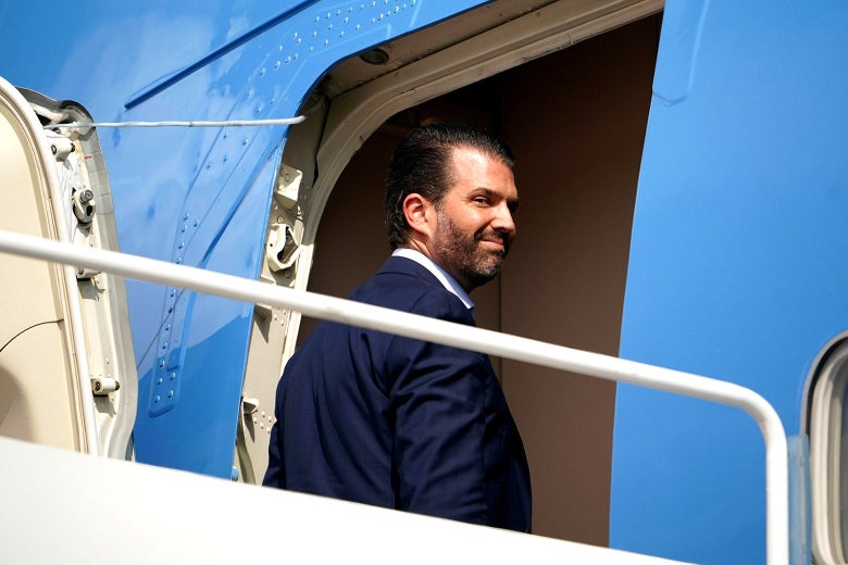 Donald Trump Jr. looks backward, smirking, as he boards Air Force One.