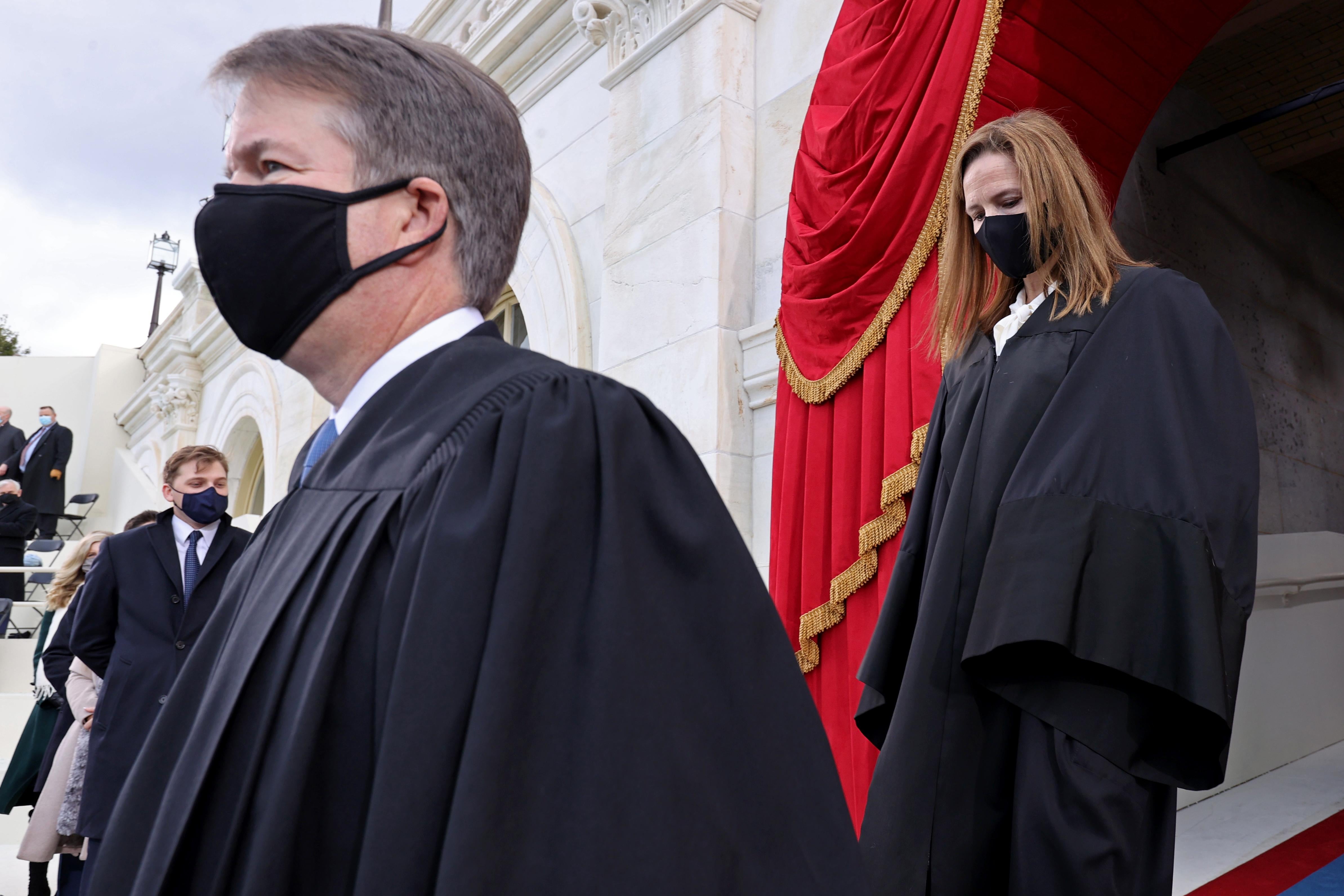 Kavanaugh and Barrett, both wearing robes and black masks, walking toward the inauguration stage at the Capitol