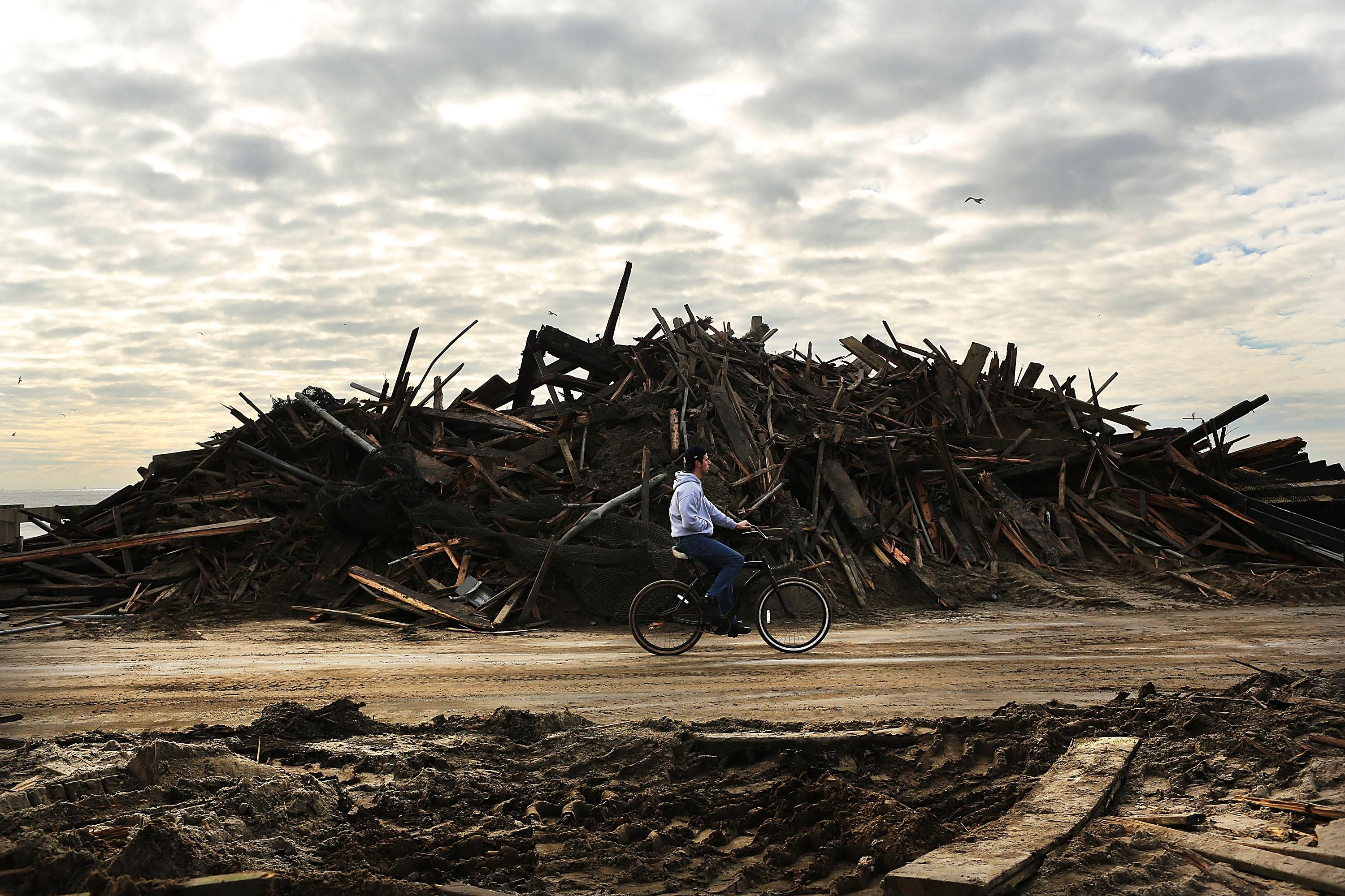 A man rides his bike through the heavily damaged Rockaway neighborhood, in Queens where a large section of the iconic boardwalk was washed away on November 2, 2012 in New York.