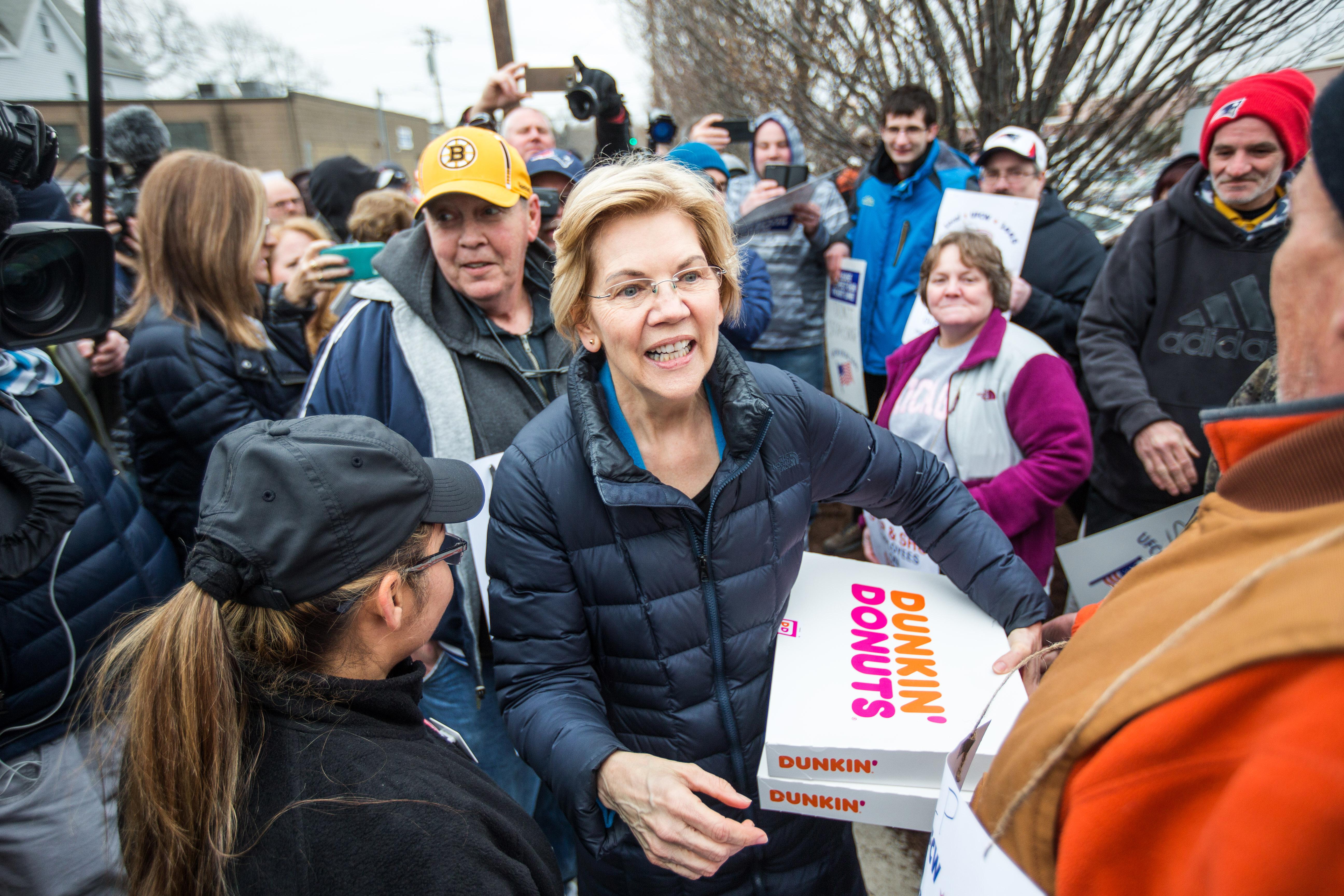 Elizabeth Warren holds two boxes from Dunkin' Donuts amid a crowd of strikers.