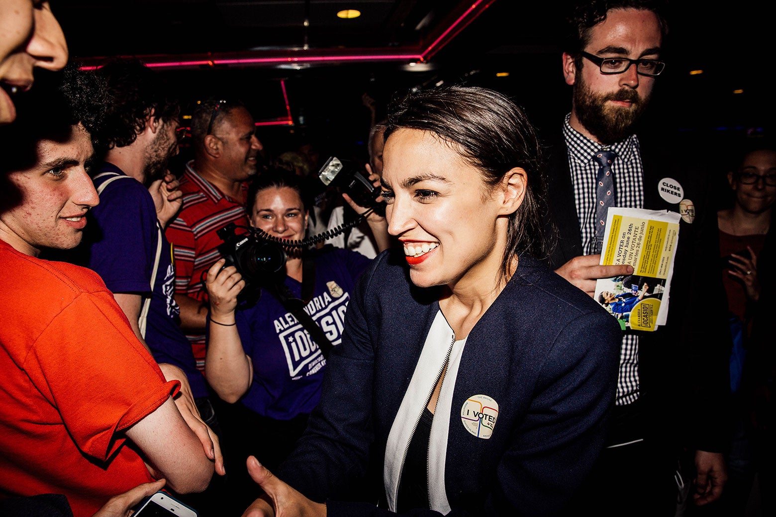 Alexandria Ocasio-Cortez smiles and shakes supporters hands her a victory party