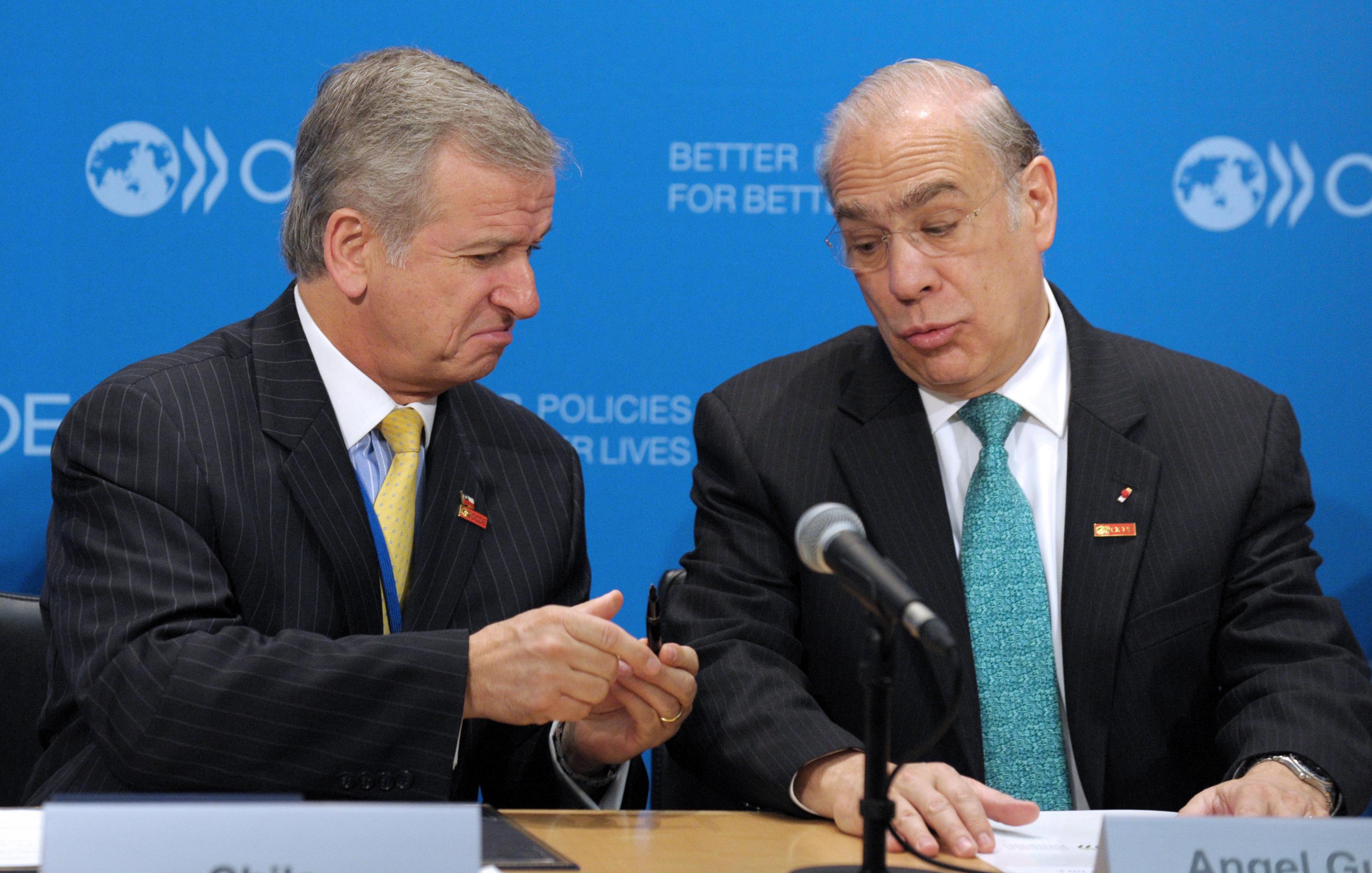 Chile Minister of Finance Felipe Larrain and OECD General Secretary Angel Gurria joke about the pen before the signing by Chile of a letter of intention to sign an OECD multilateral convention on mutual administrative assistance in tax matters during a signing ceremony at the OECD headquarters in Paris on May 29, 2013.