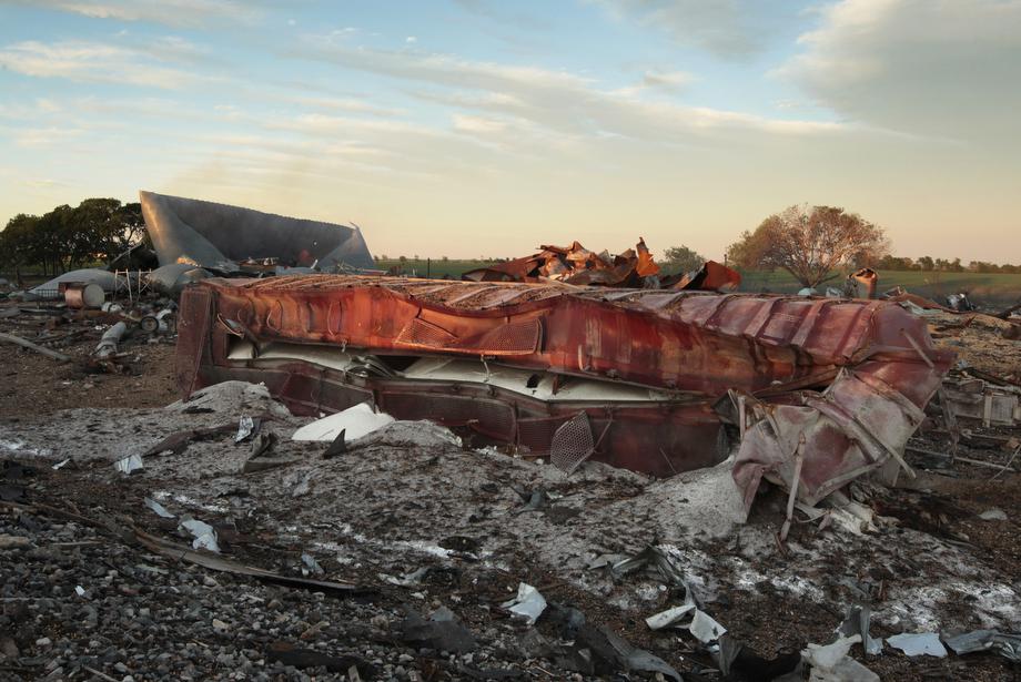 A railroad boxcar filled with ammonium nitrate lays on its side near to the remains of the fertilizer plant that exploded yesterday afternoon on April 18, 2013 in West, Texas.