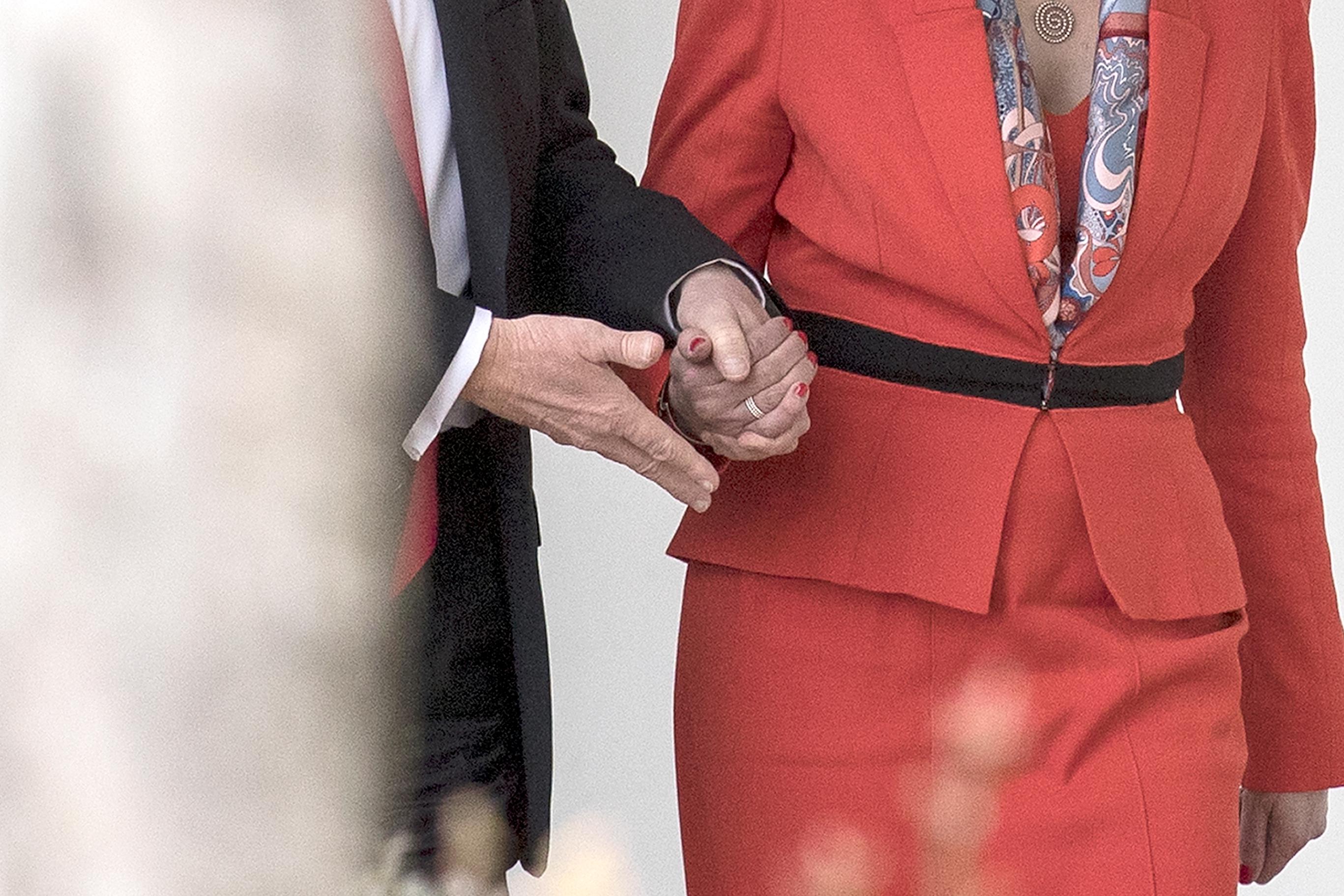 Donald Trump grasps Theresa May's hand as the two encounter a set of stairs.