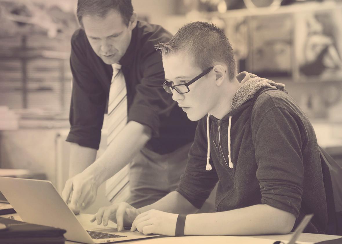 Teacher helping student use laptop in class