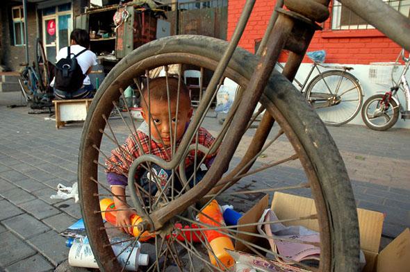 A boy plays with bottles outside his parents’ bicycle shop in the student district of Wudaokou in Beijing, May 2008.