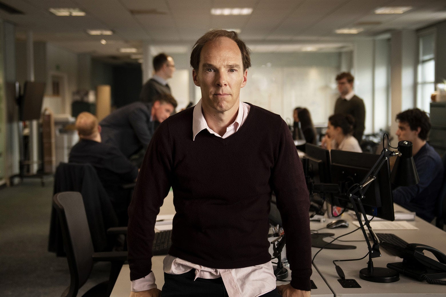 Benedict Cumberbatch, looking balding and disheveled, in an office.