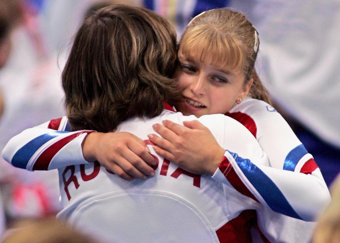 Russian Anna Pavlova is congratulated by an unindentified staff member after winning the bronze medal in the women's vault final 22 August 2004 at the Olympic Indoor Hall in Athens during the Olympics Games. 