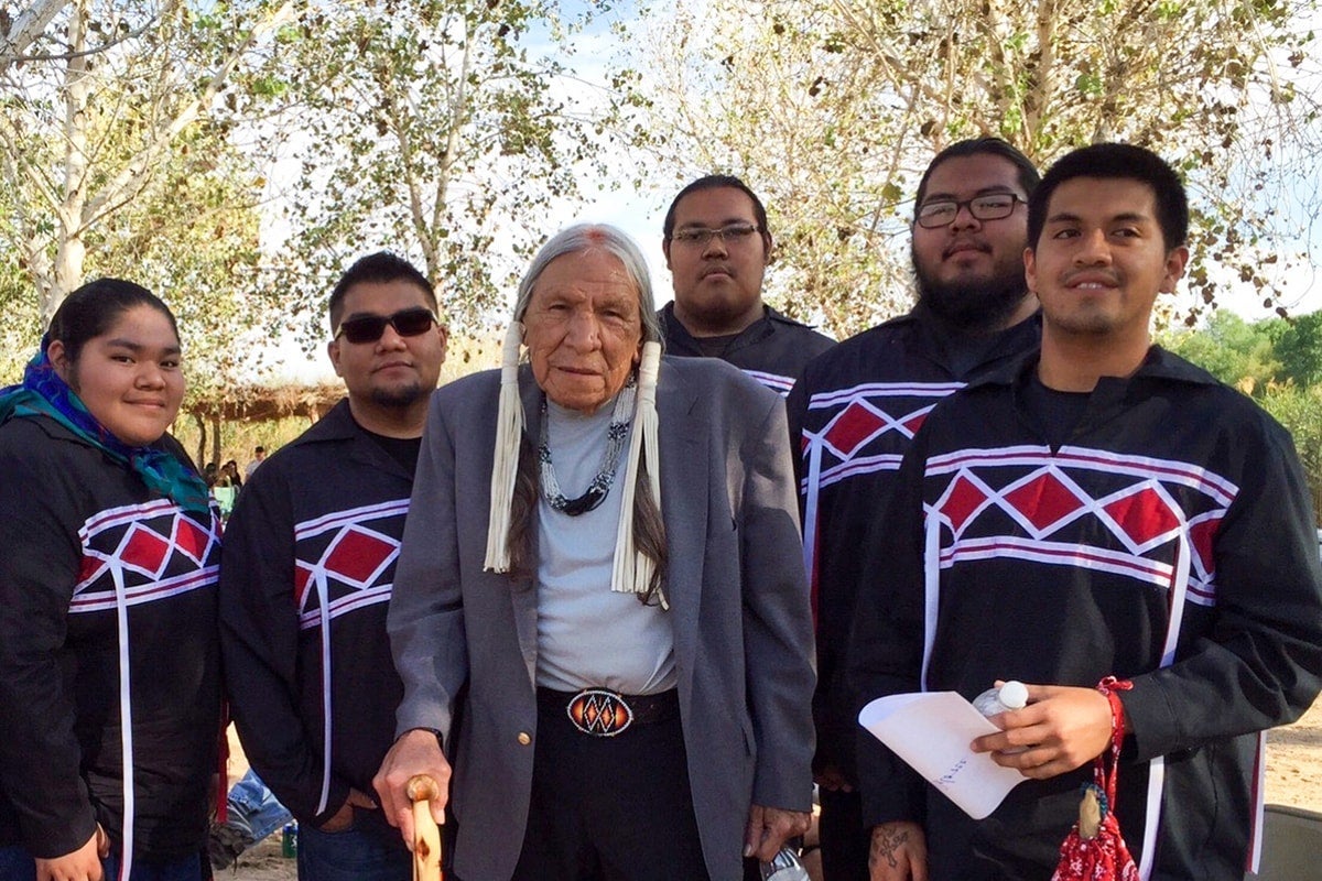 Five young Native Americans stand around an elder.