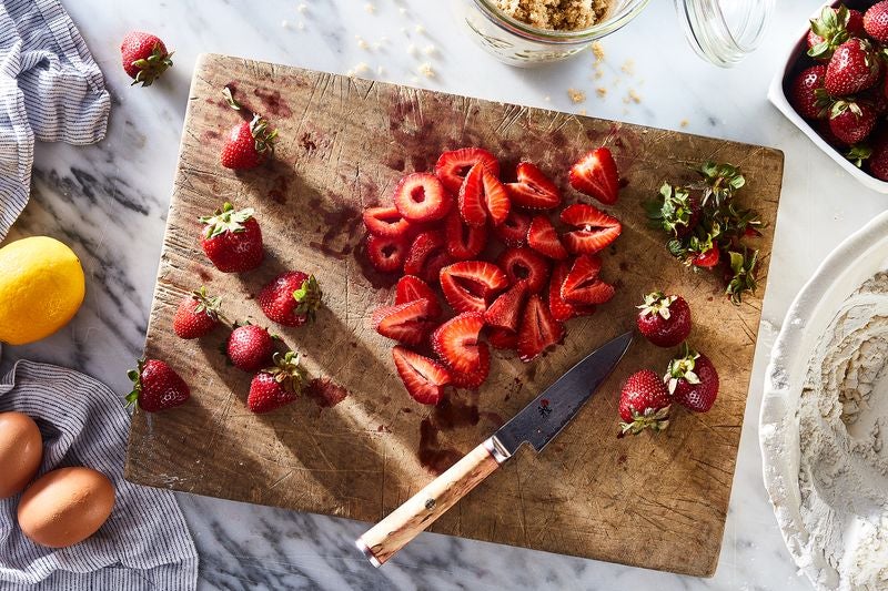 A cutting board laden with fresh, sliced strawberries.
