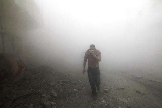 A man runs amongst rubble as smoke rises from buildings damaged by what activists said were missiles fired by a Syrian Air Force fighter jet loyal to President Bashar al-Assad in Raqqa province, eastern Syria, March 12, 2013. 