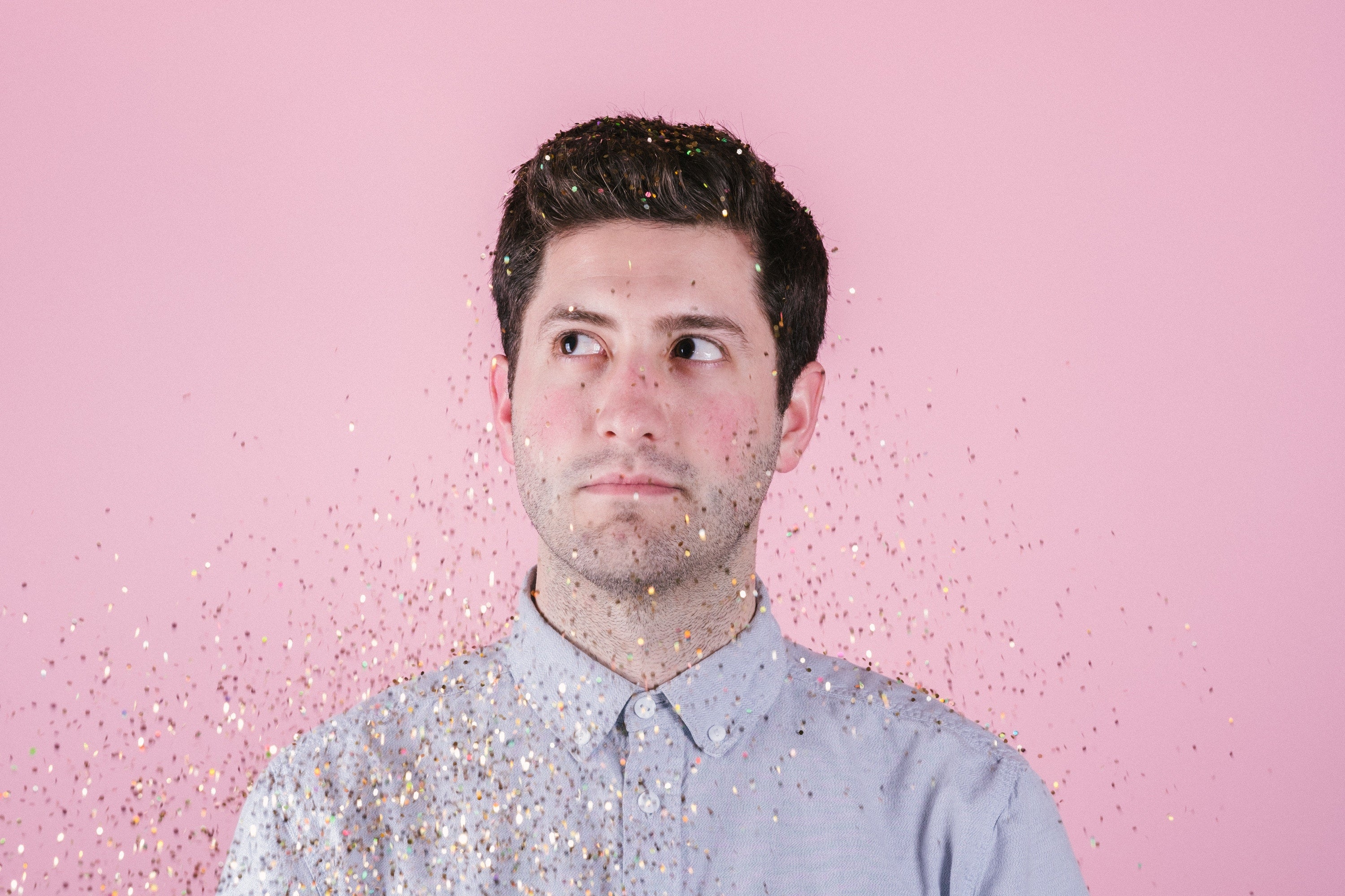 A man in a button-down shirt with glitter in the air. 
