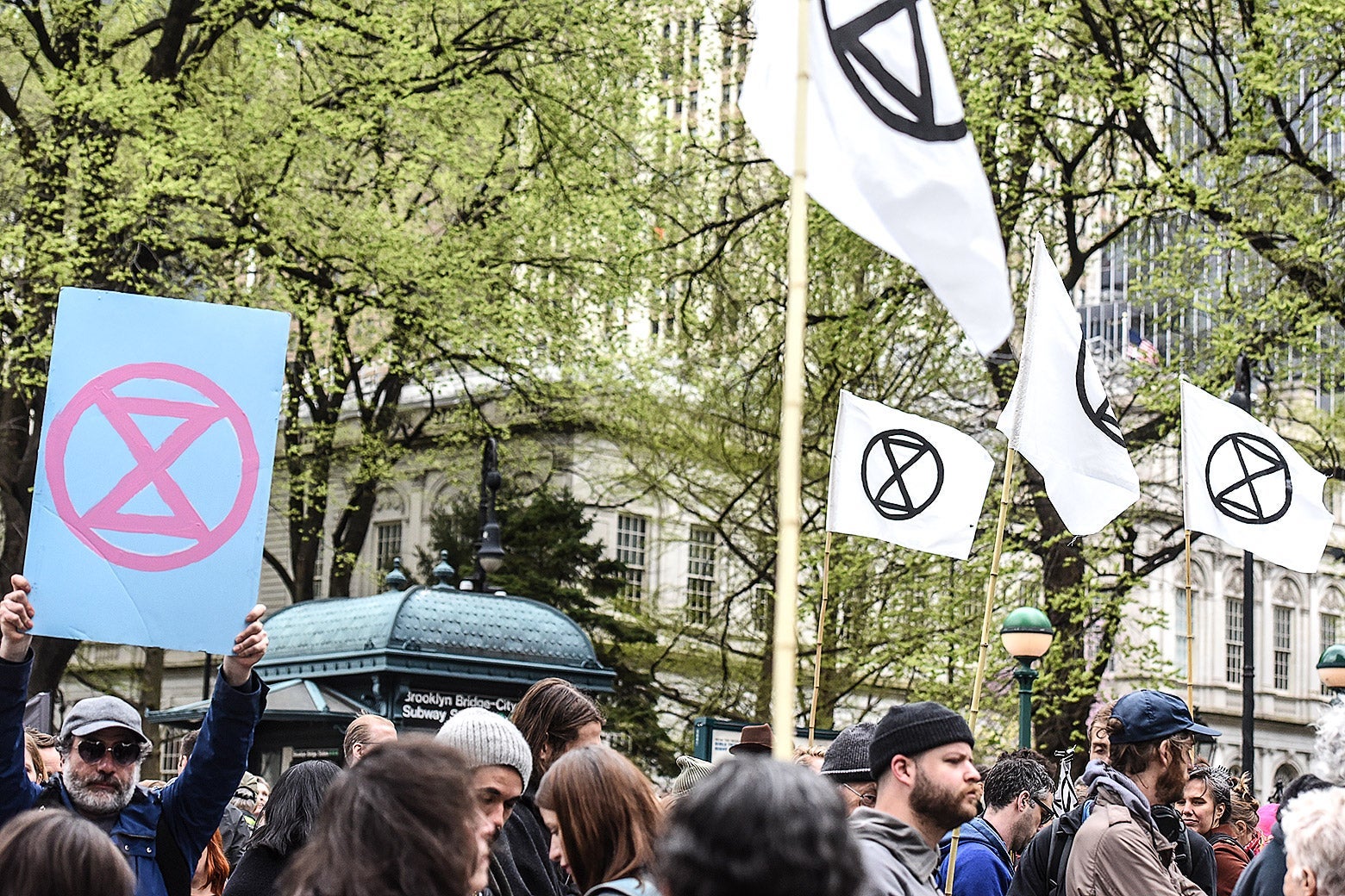 Protesters hold signs displaying the extinction symbol, which shows a circle with two triangles.