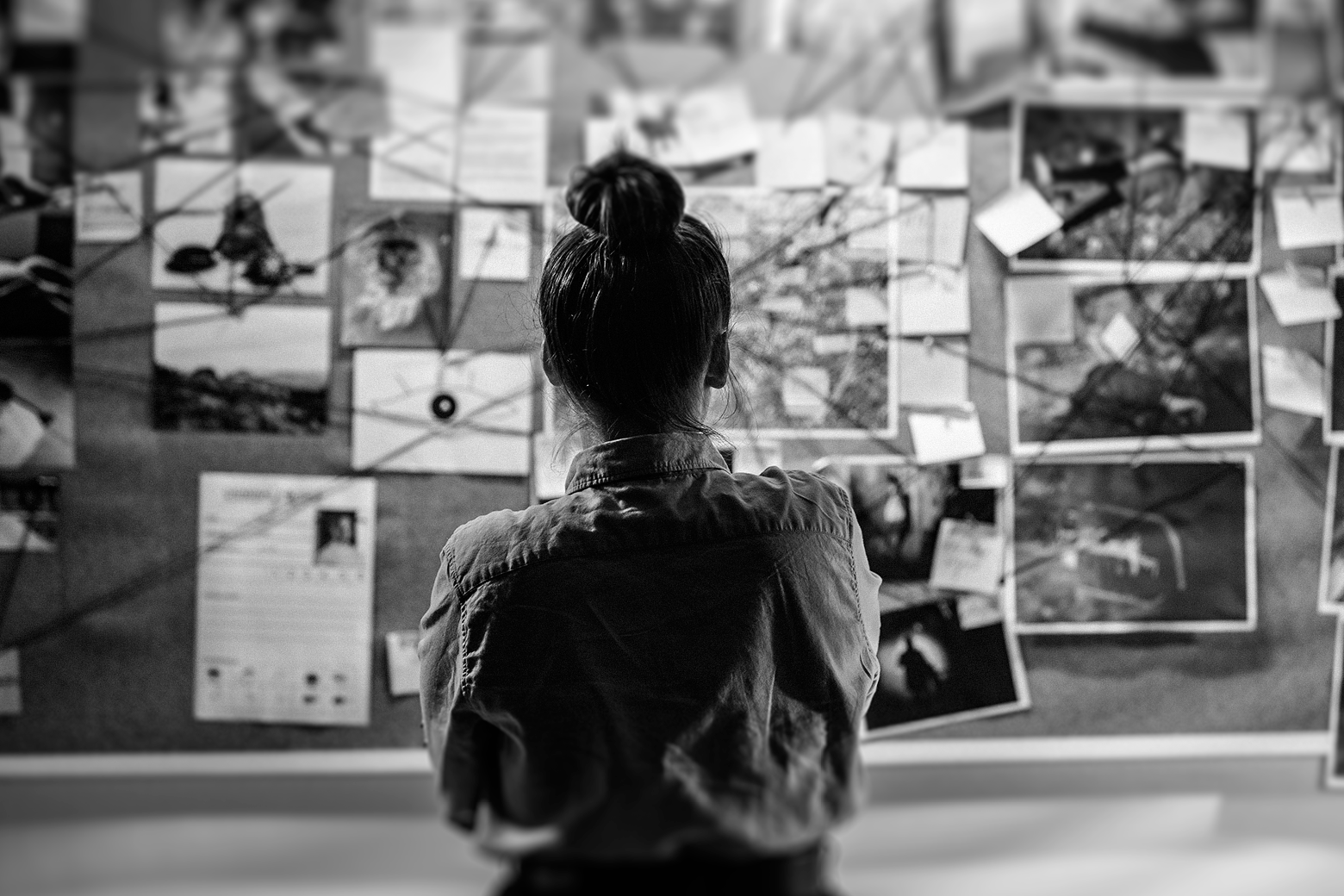 Woman in front of a police department-esque murder investigation board