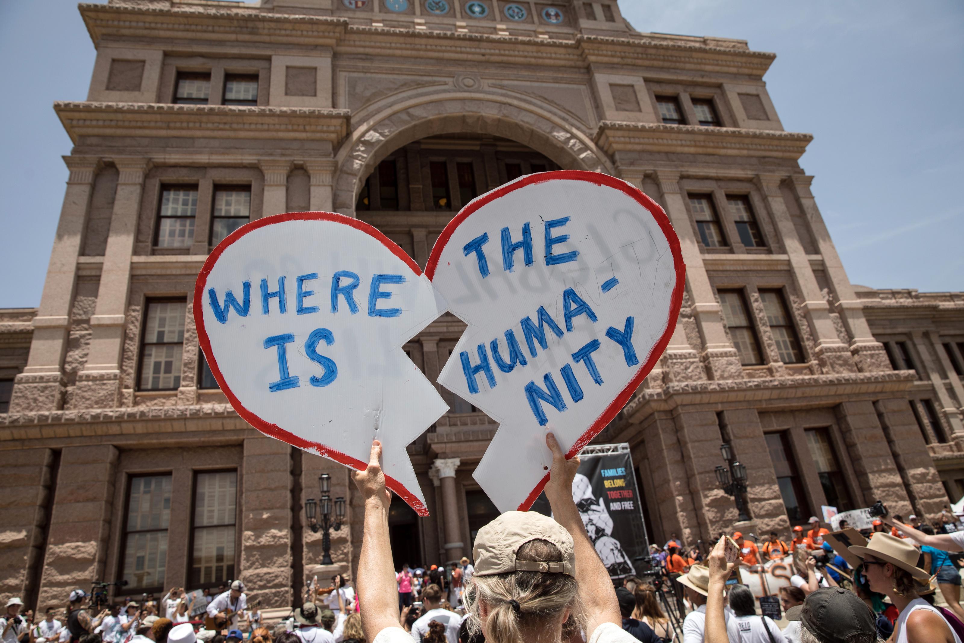 A demonstrator holds up a protest sign during a rally against the Trump administration's immigration policies outside of the Texas Capitol in Austin, Texas, on June 30, 2018.