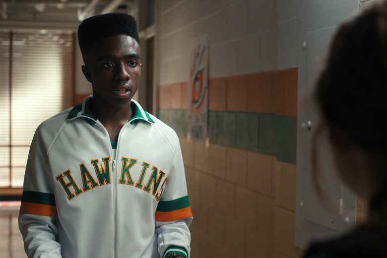 Lucas stands in a high school hallway wearing his basketball warmup jacket.