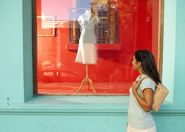 Young woman looking in shop window, side view.