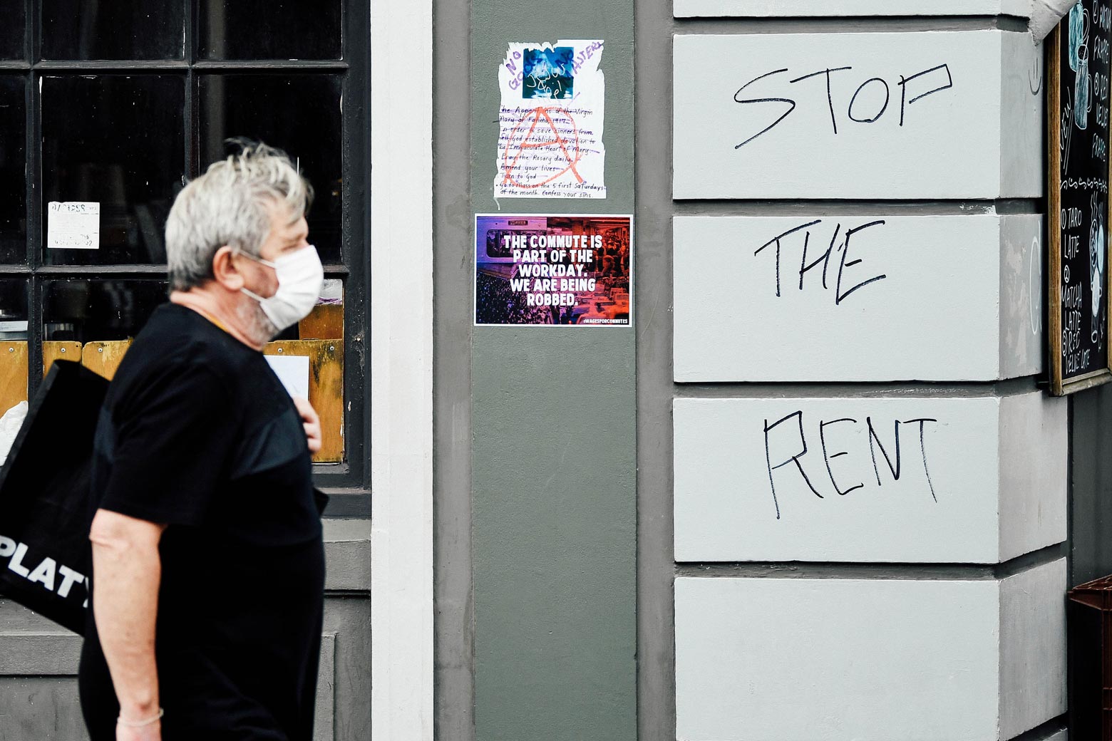 A man walks past a sign saying Stop the Rent on King Street in Newtown in Sydney, Monday, March 23, 2020. The state of NSW is shutting down all non-essential services to slow the rapidly spreading.
