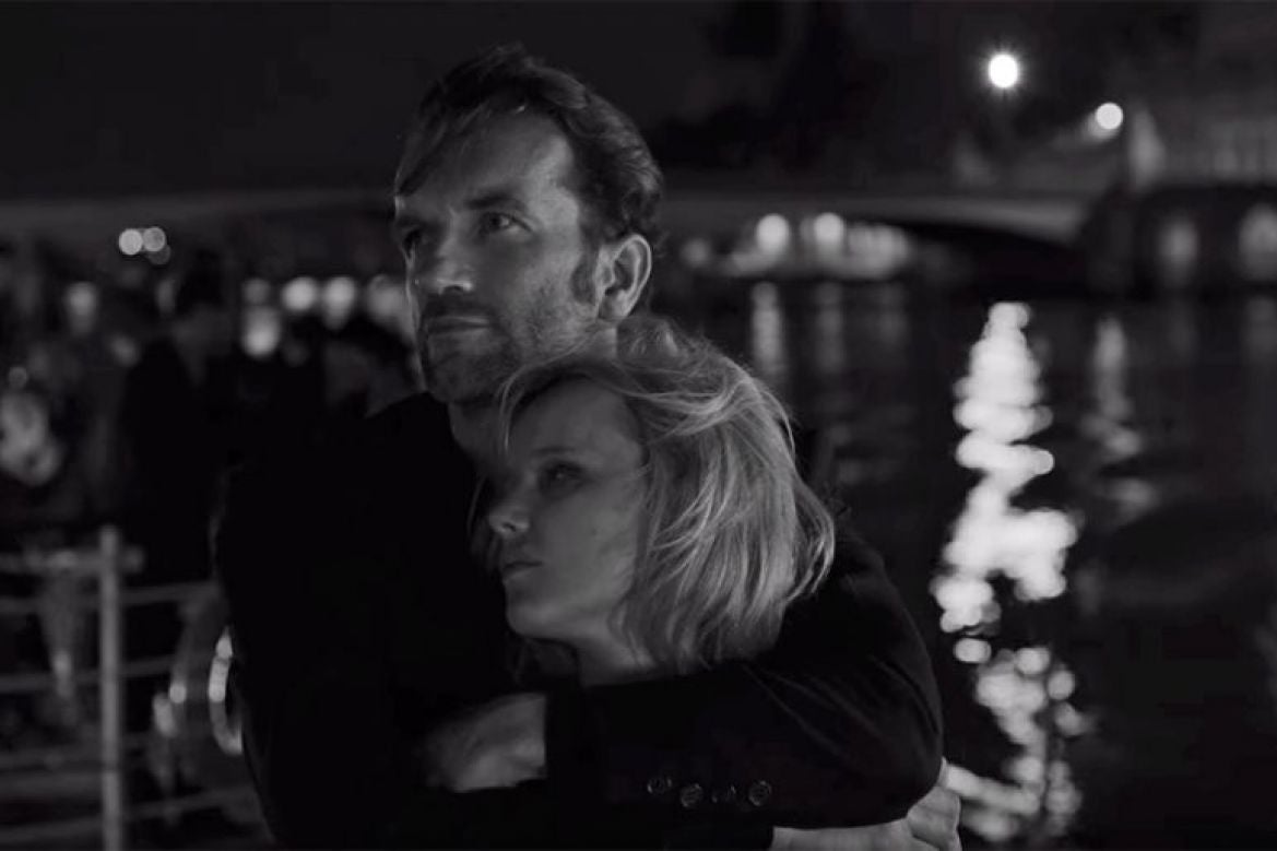 A man hugs a woman to his chest. The image is greyscale.
